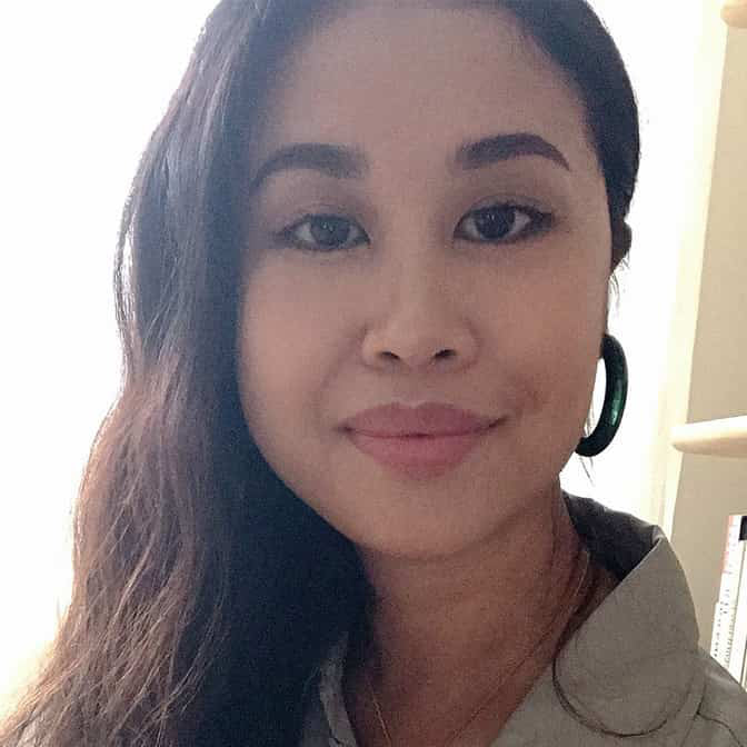 Bernadette Pascua close-up, wearing tan shirt and green resin hoop earring