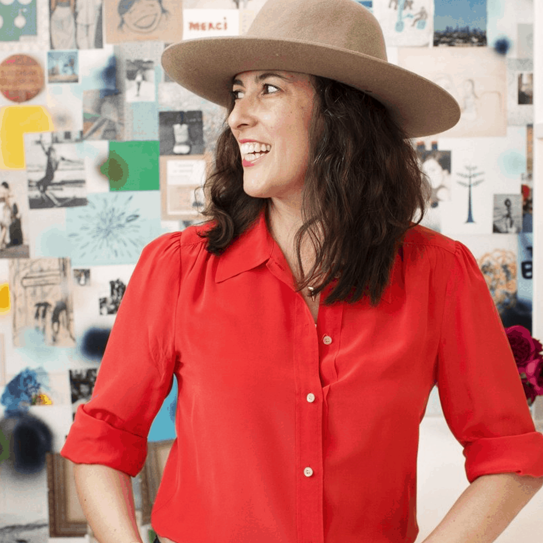 Clare Vivier stands against collage wall, wearing red button-down shirt with tan hat