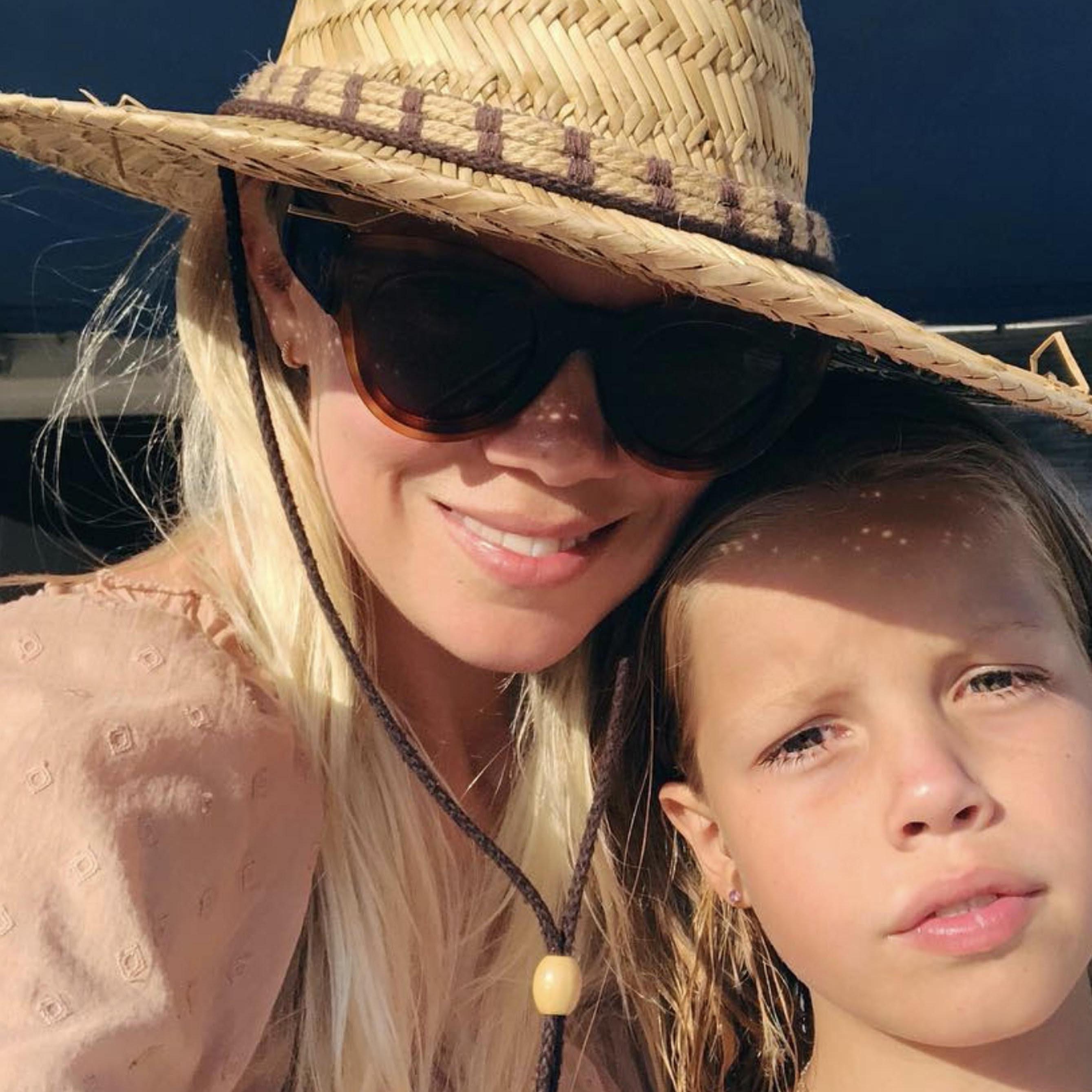 Jessie Randall with child, wears sunglasses, straw hat and pink top