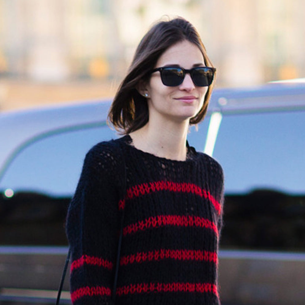 Woman in sunglasses wears black and red striped sweater