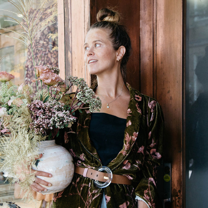 Taylor Patterson standing in window holding white vase full of flowers