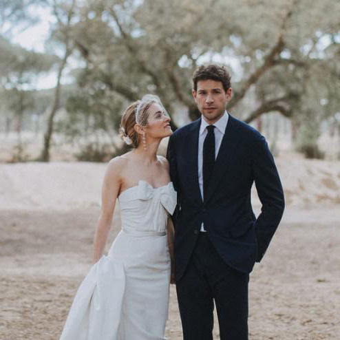Kathryn and her groom in wedding attire, standing in an orchard