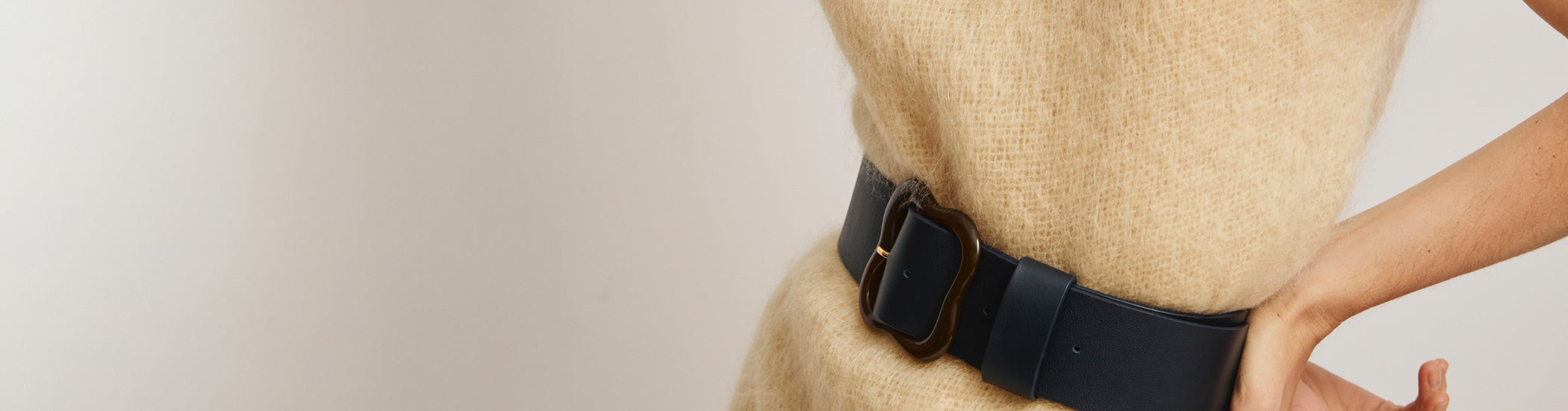 Model's torso on grey backdrop wearing fuzzy tan dress with Florence Belt in Navy