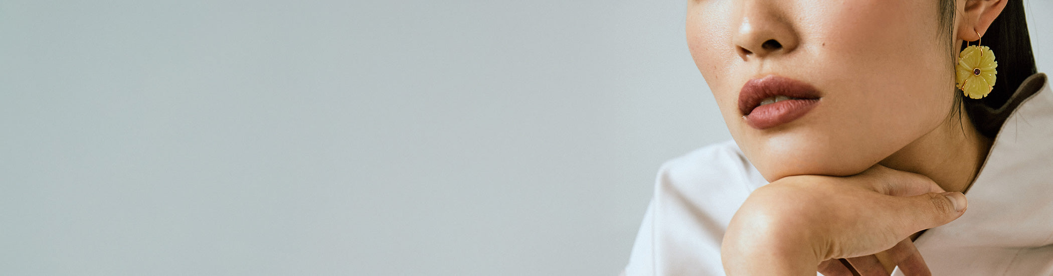 Model on grey backdrop wears white top with New Bloom Earrings in Canary