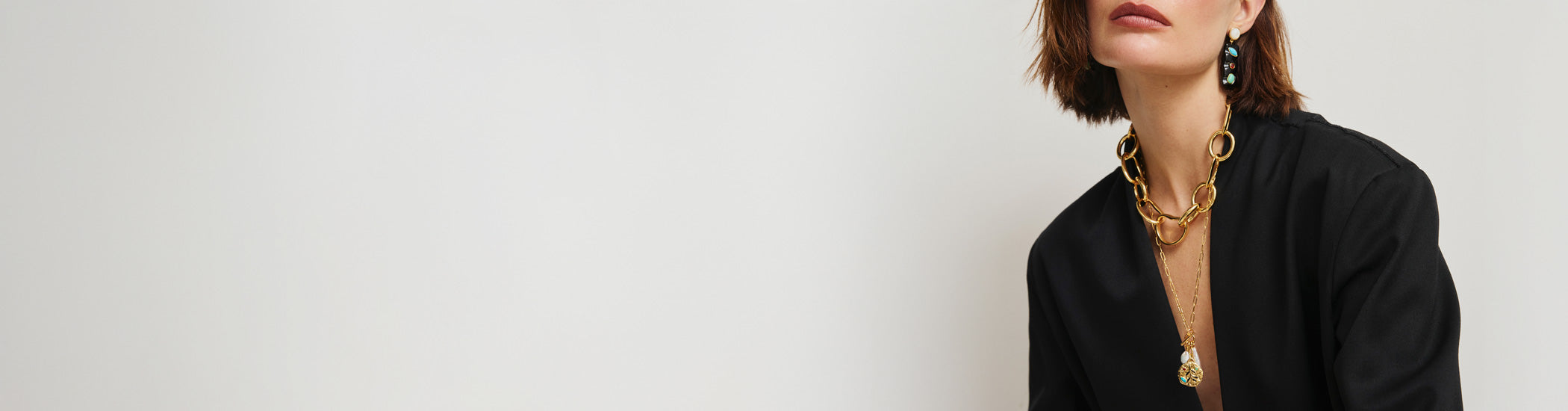 Model on grey backdrop wears black blazer with Tessera Earrings, Campo Charm Necklace and Porto Chain