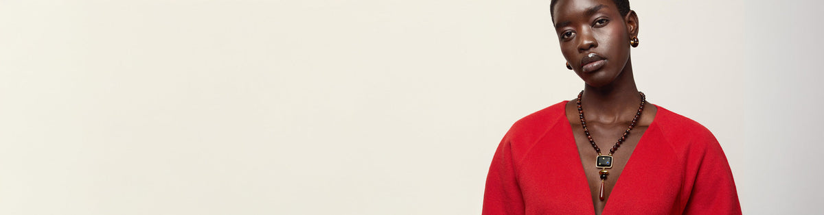 Model in red jacket wears Piedra Necklace and Mini Organic Hoops in Cherry