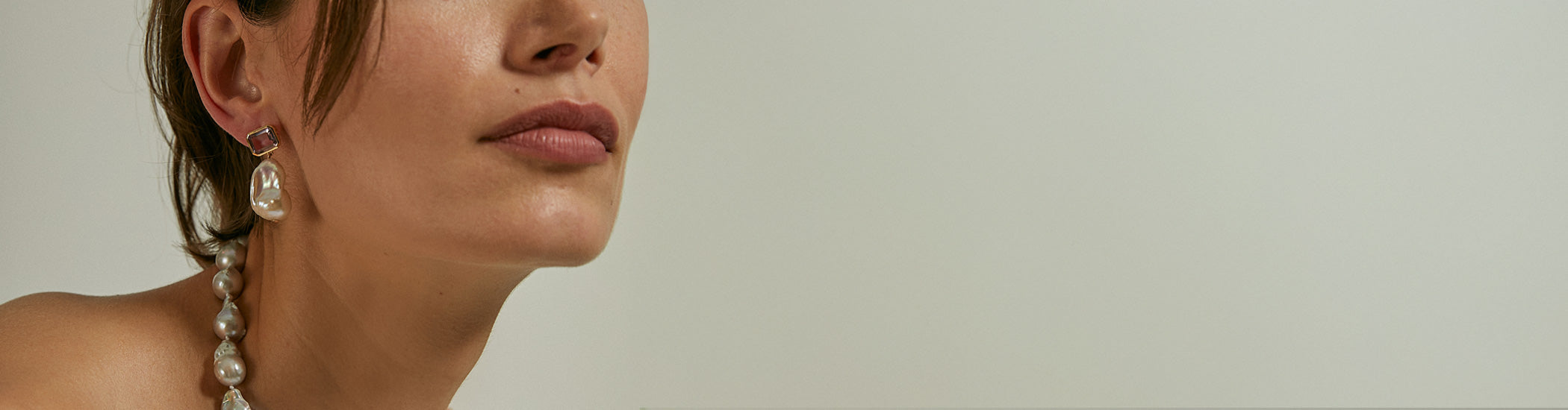 Model on grey backdrop wears Juno Earrings in Pink Amethyst