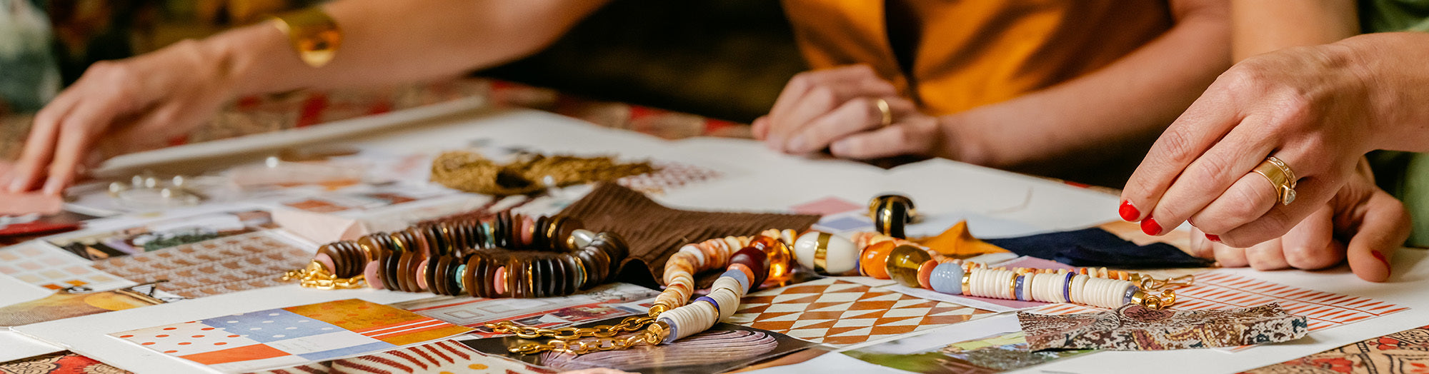 Model on tan stone wall wears cream top with stacked chunky bead necklaces