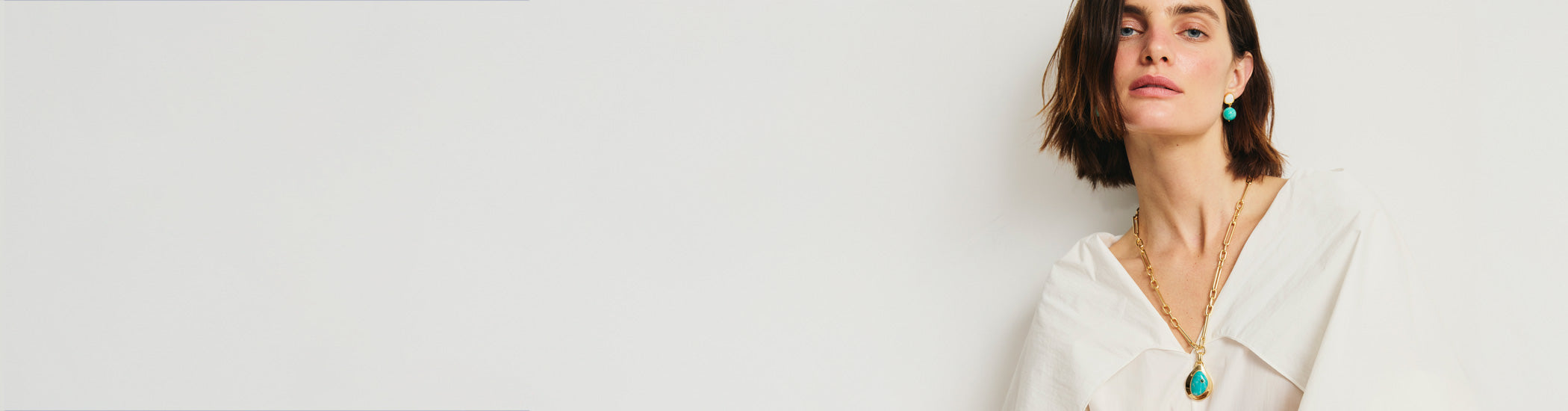 Model on light grey backdrop wears white top with Pond Necklace and Rio Earrings