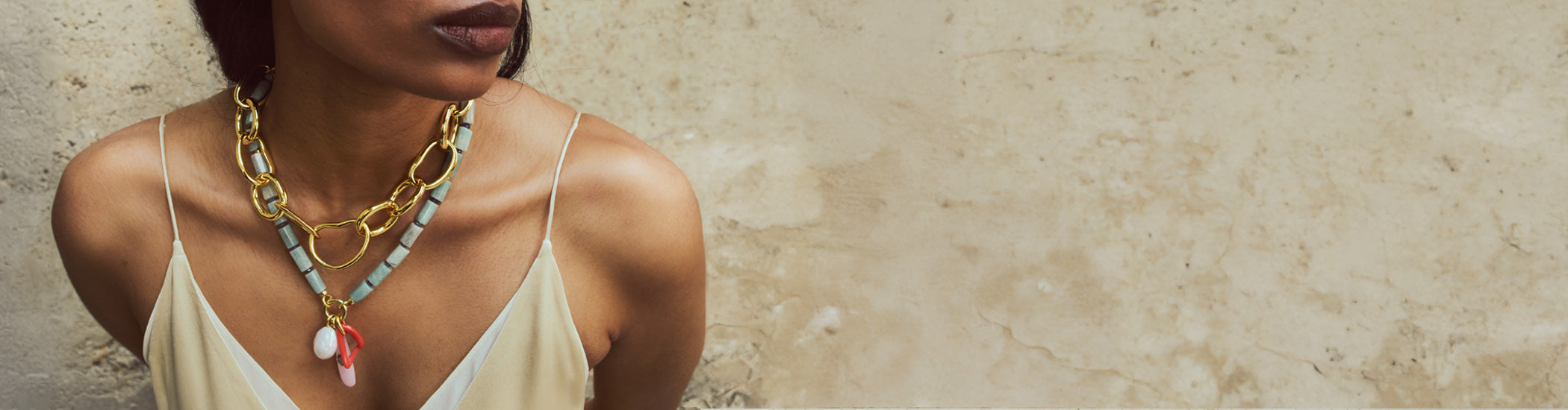 Model on stone backdrop wears slip dress with Cortez Necklace and Porto Chain