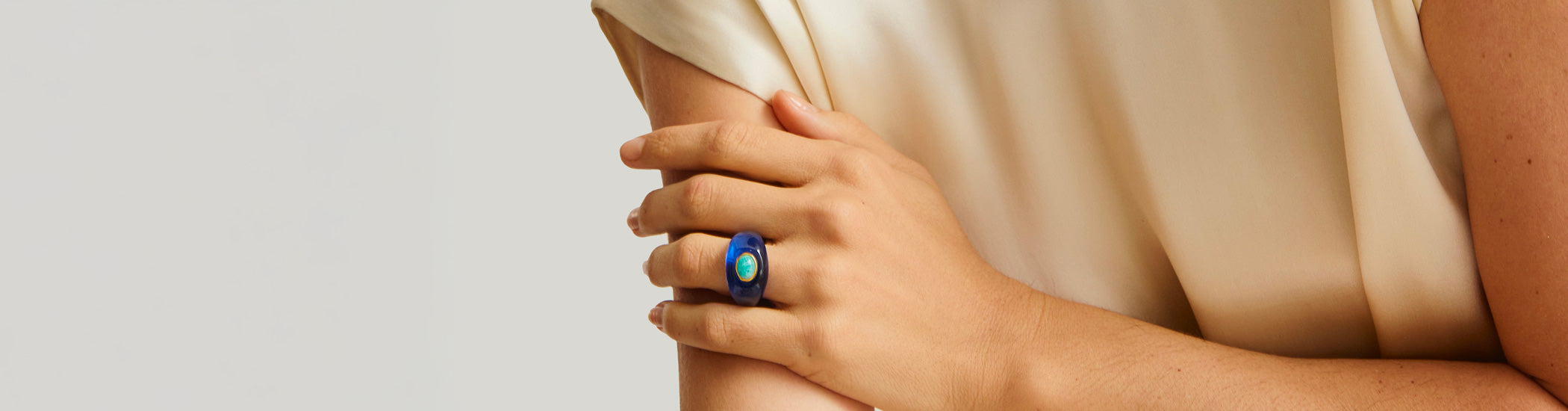 Model on tan stone backdrop holds hand to neck and wears Monument Ring in Leopard
