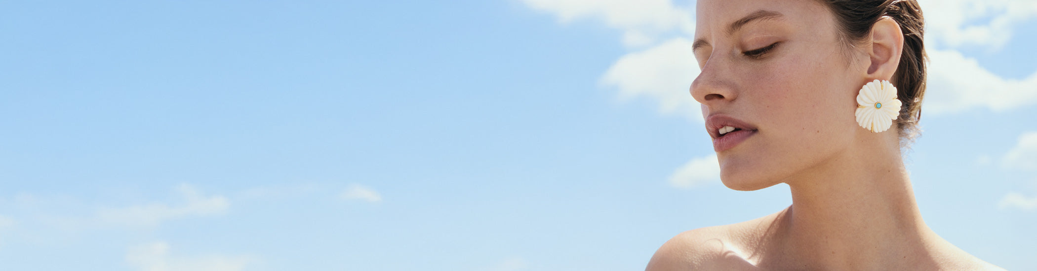 Model on sky backdrop wears New Bloom Stud Earrings in Pearl