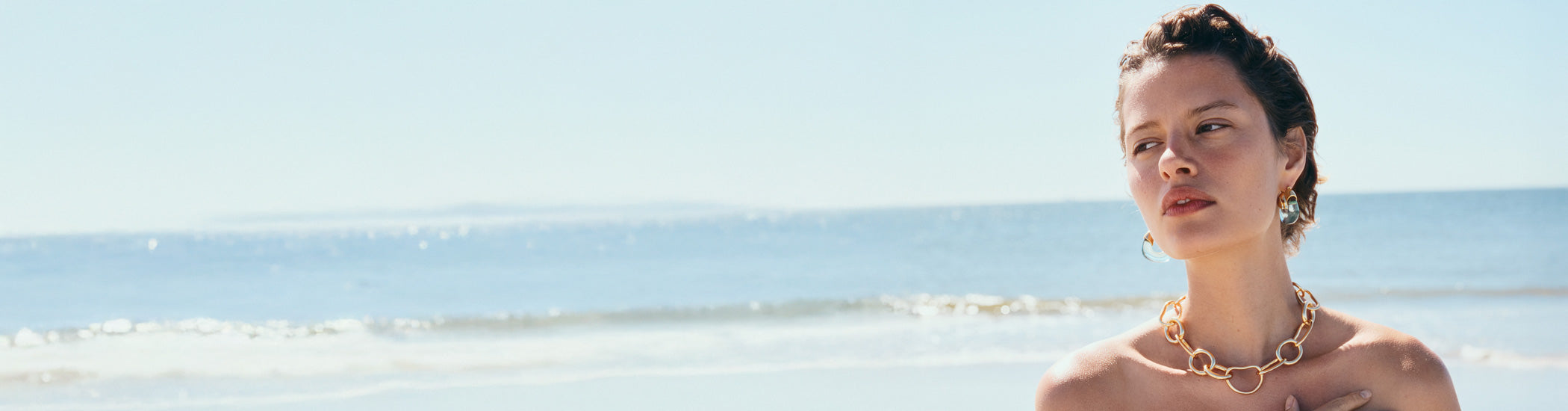 Model at ocean wears Organic Hoops in Lagoon and Porto Chain in Gold