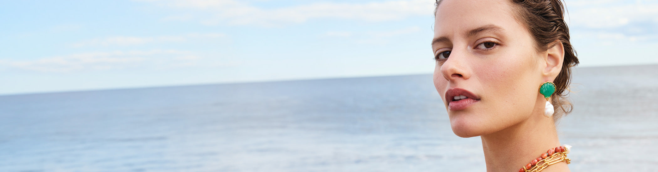 Model on beach wears Marina Drop Earrings