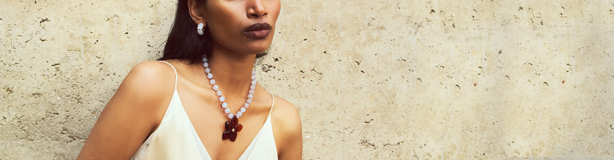 Model on grey backdrop wears pink top with Galina Earrings in Sangria