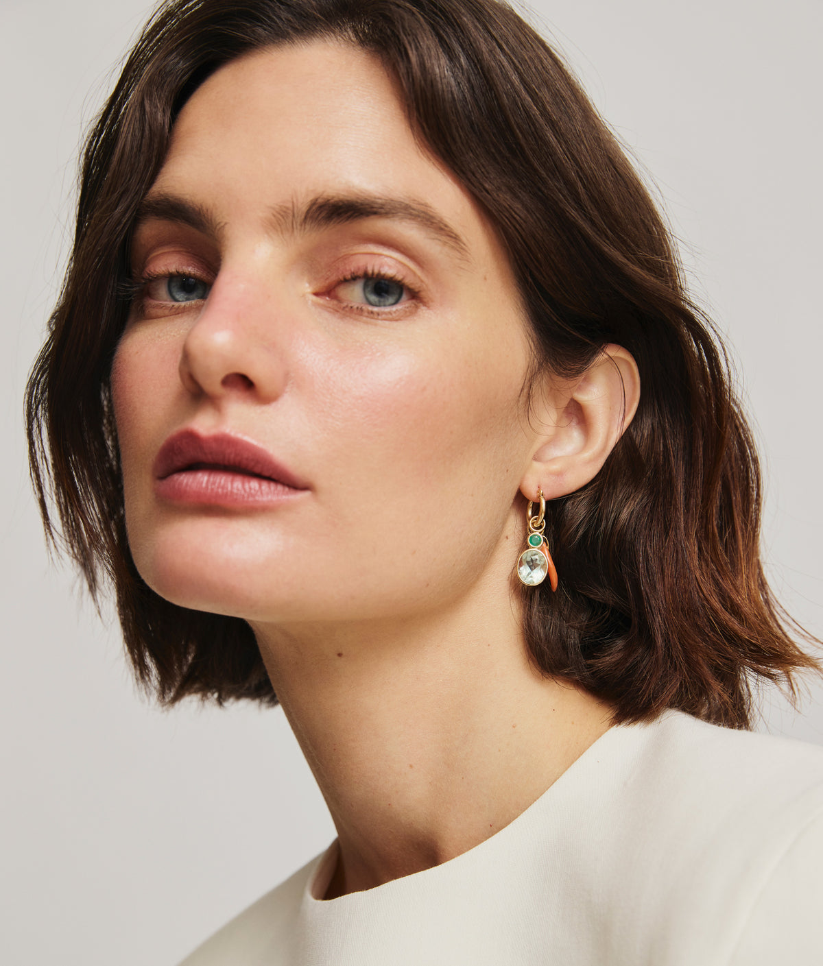Model in white top wears Gold Mood Hoops in Lucky Charms, alternate ear view.