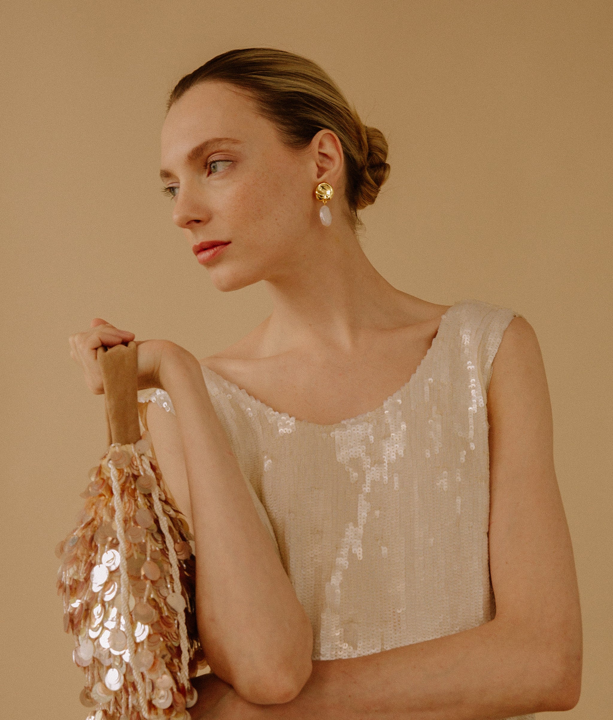 Model in sequin top wears Coin Reflection Earrings in Gold.