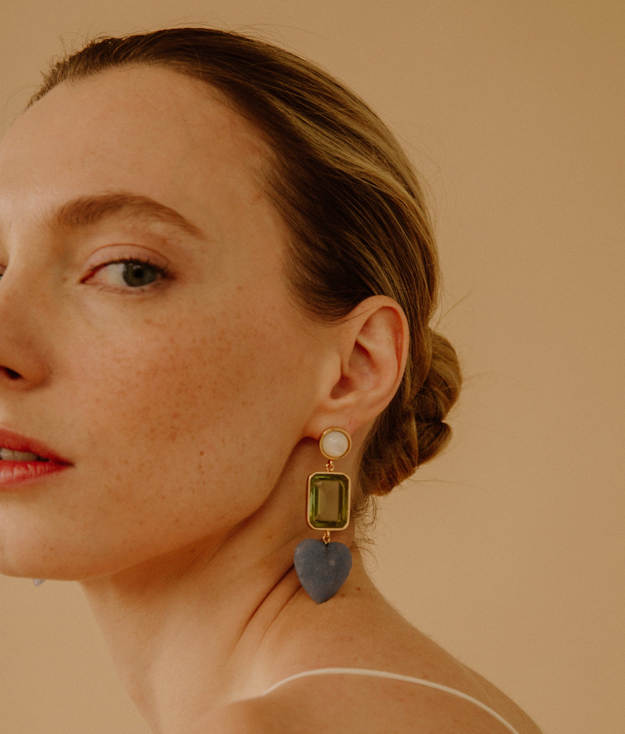 Model wearing the Demy Earrings in Azul on a tan background.