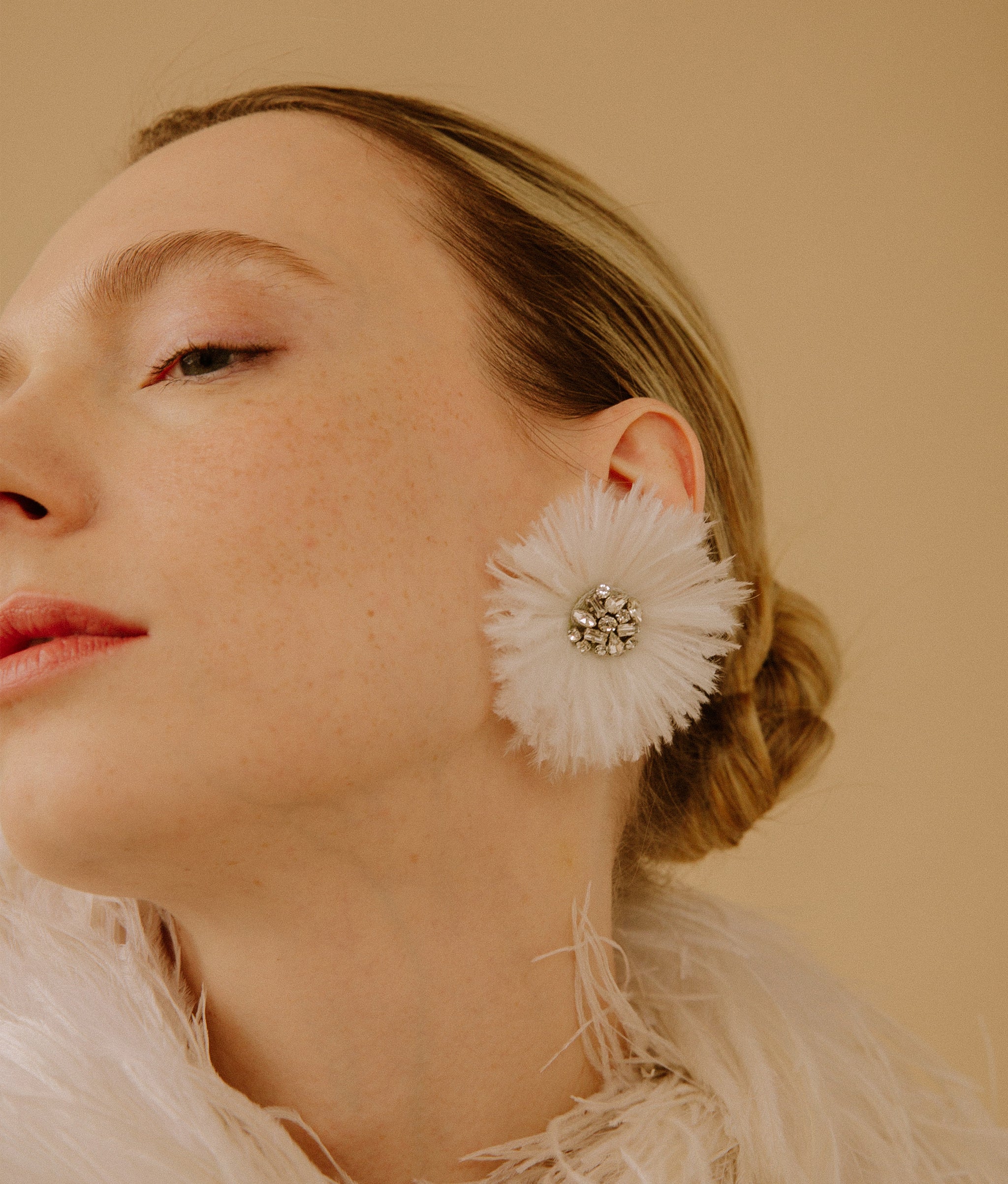 Model on tan background wearing the Plume Earrings in White.