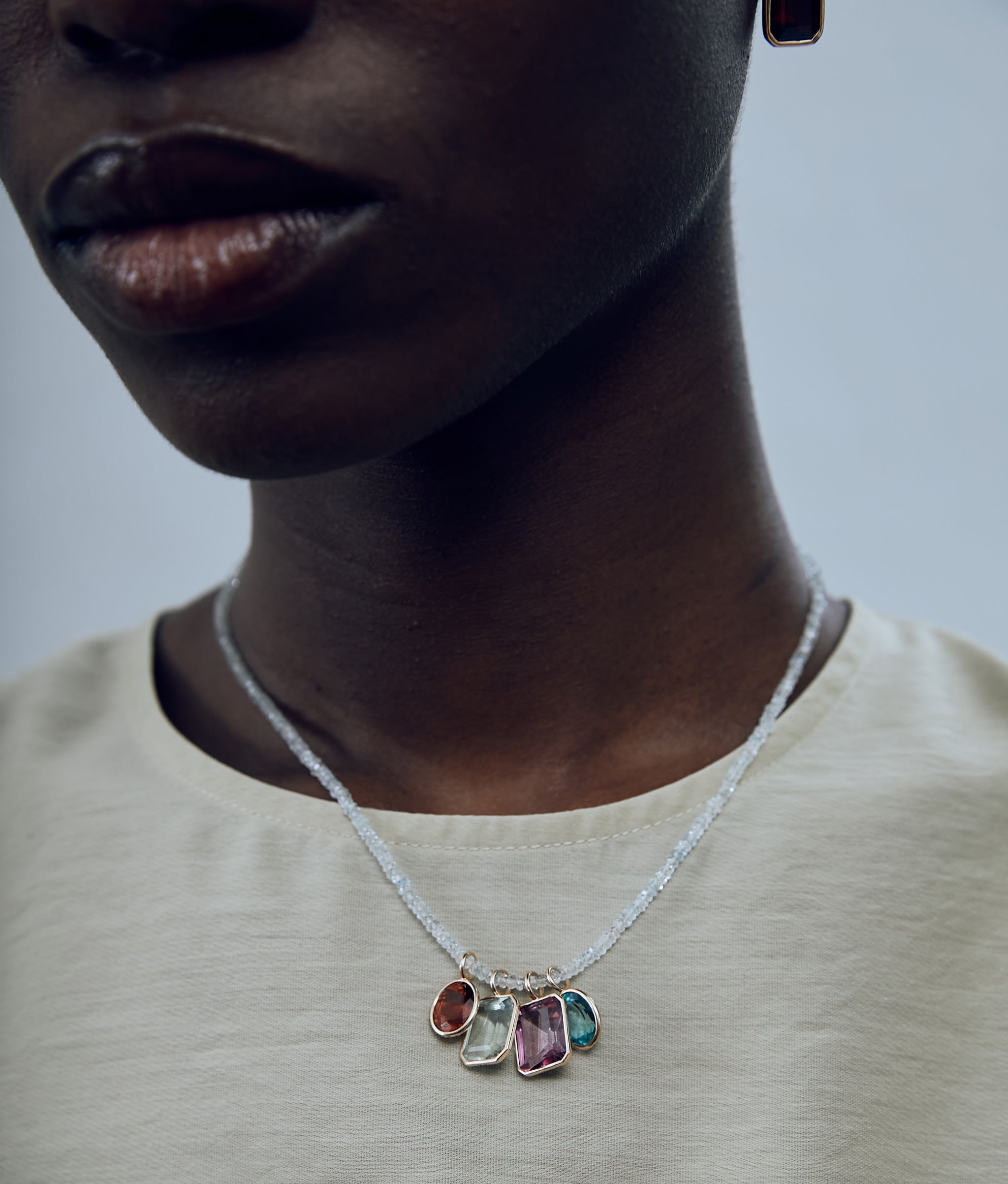 Model wearing Singular Oval 14k Gold Necklace Charm in Hessonite Garnet on a fine mood necklace, with other fine charms.