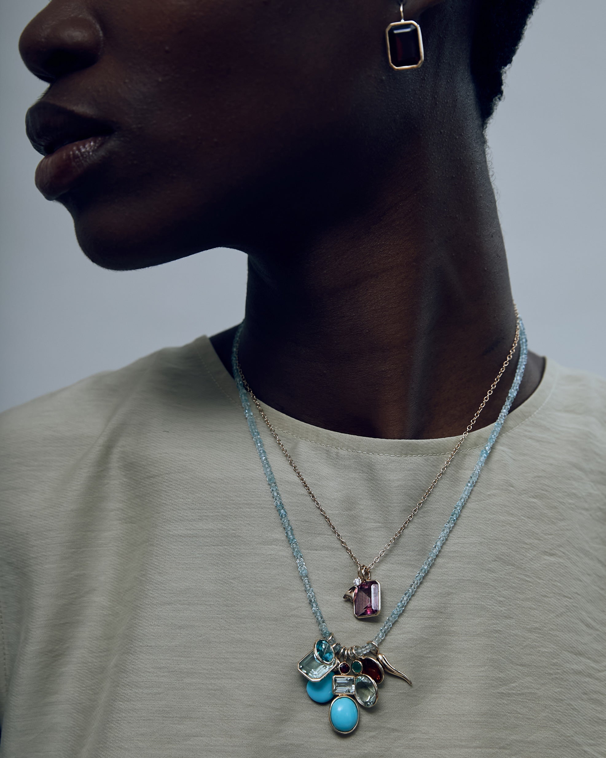 Model with Singular Rectangle 14k Gold Necklace Charm in Pink Topaz on a fine mood necklace, with other fine charms.