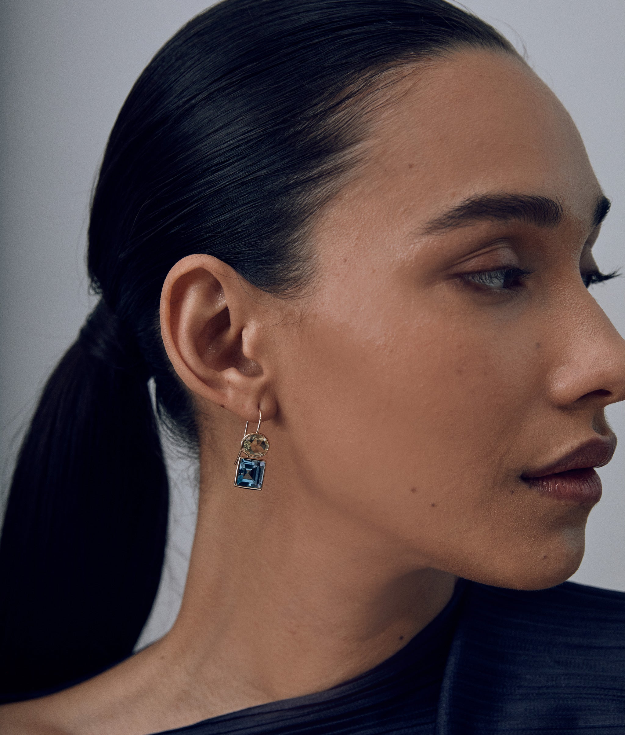 Model in profile wears black top with 14k Gold Duo Earrings in Lemon Quartz and Sky Blue Topaz
