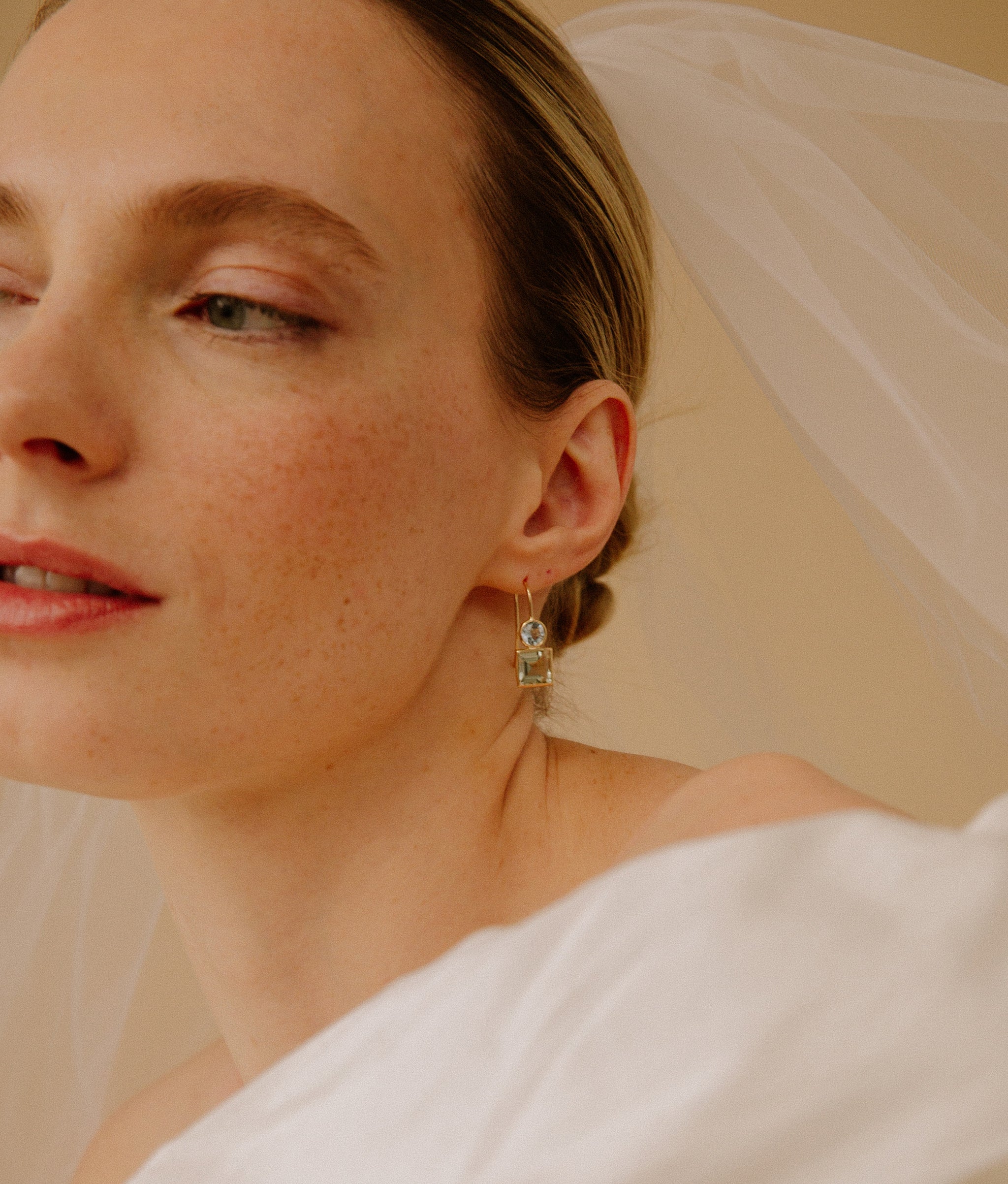 Close-up of model in veil and 14k Gold Pastille Earrings in Sky Blue Topaz and Green Amethyst