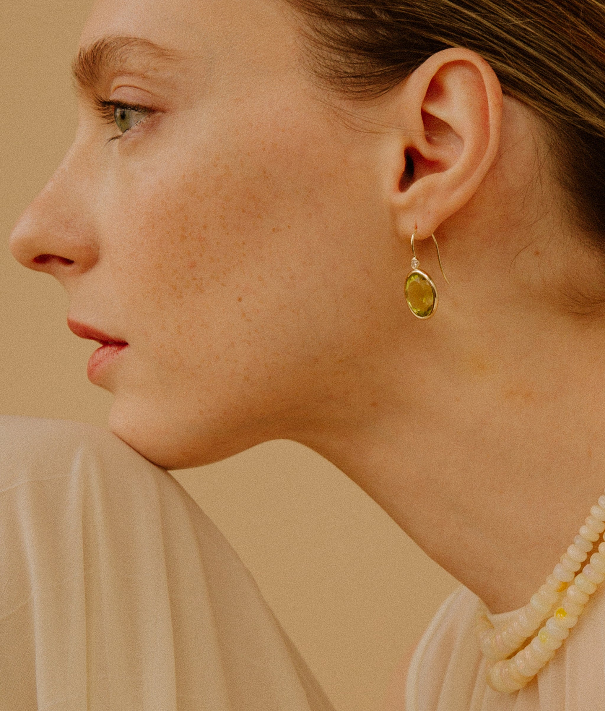Close-up of model on tan backdrop with 14k Gold Pool Earrings in Lemon Quartz & Diamond and Opal Necklaces.