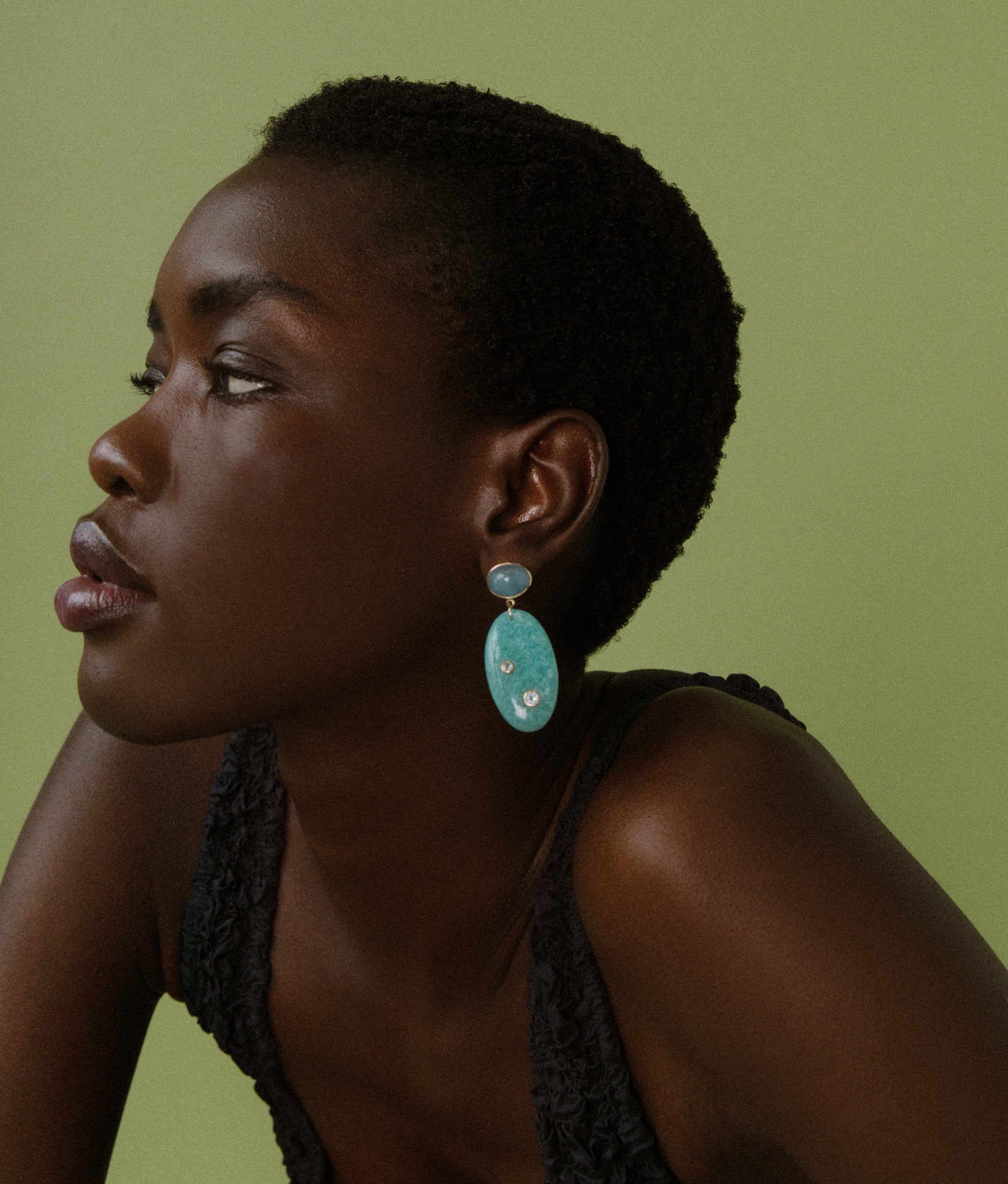 Model on green backdrop wears black tank with 14k Gold, Aquamarine & Amazonite Earrings.