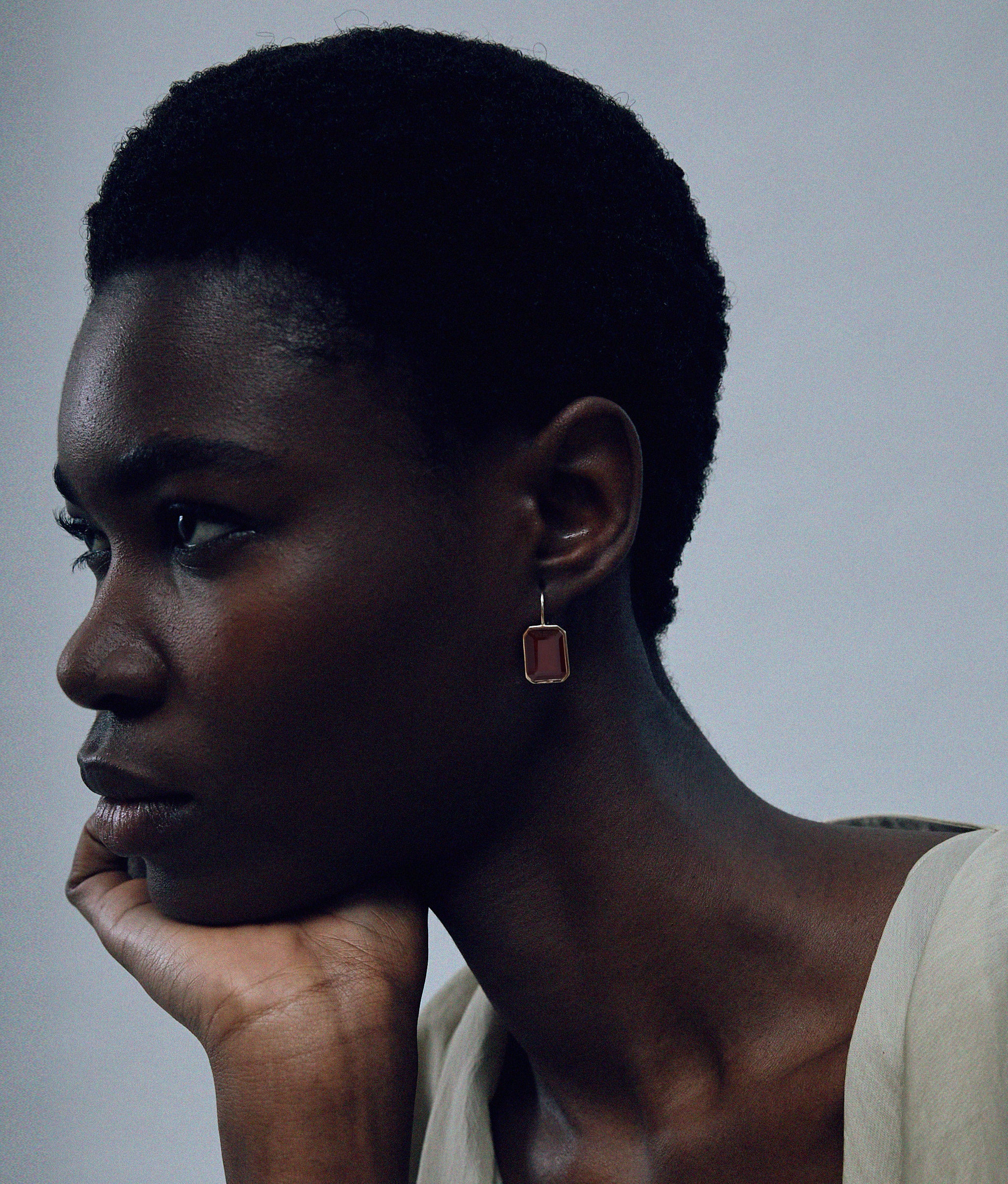Another angle of model on grey background wearing the Aria Earrings in Hessonite Garnet.