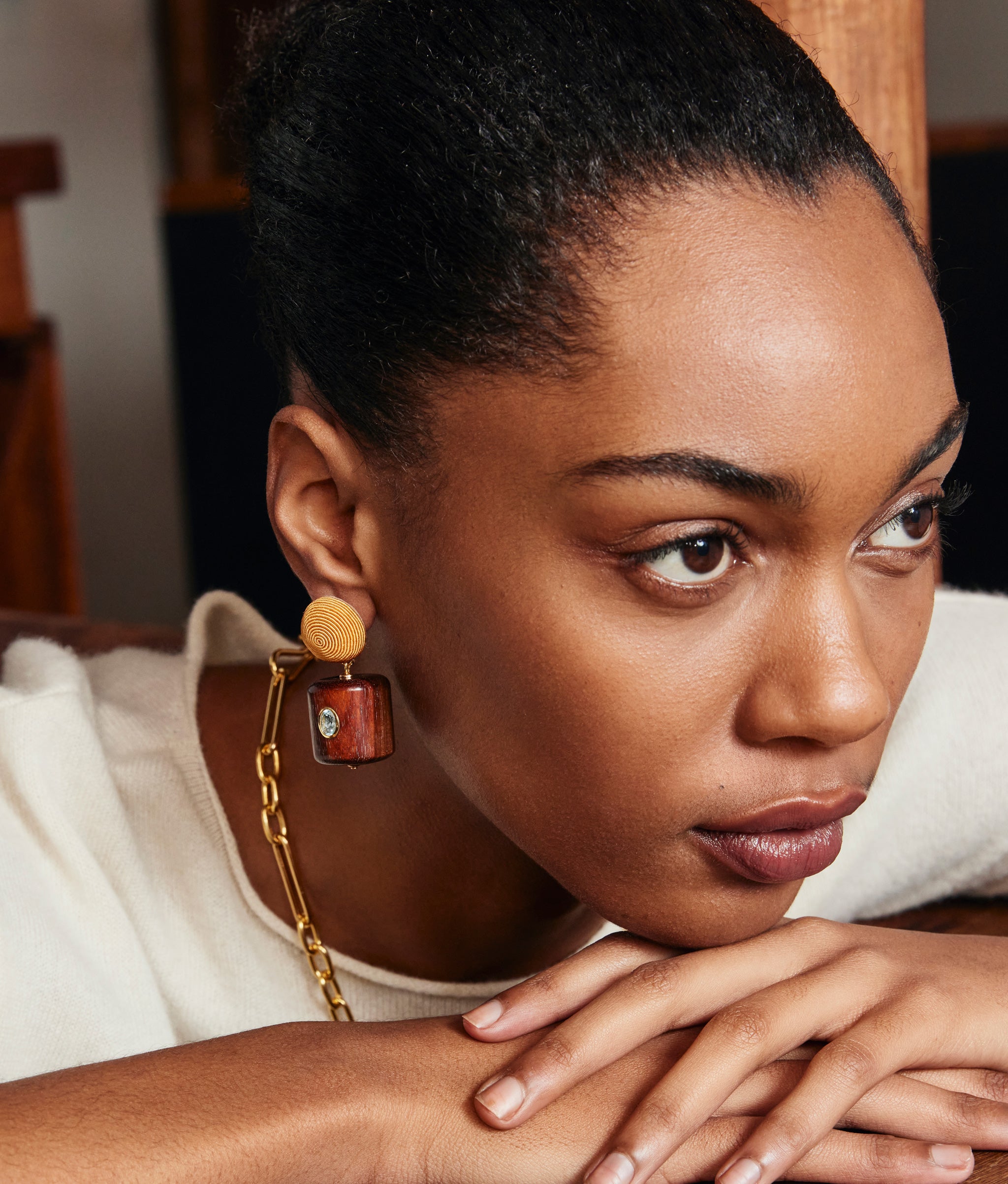 Model poses with hands under chin and wears cream top with Lantern Earrings.