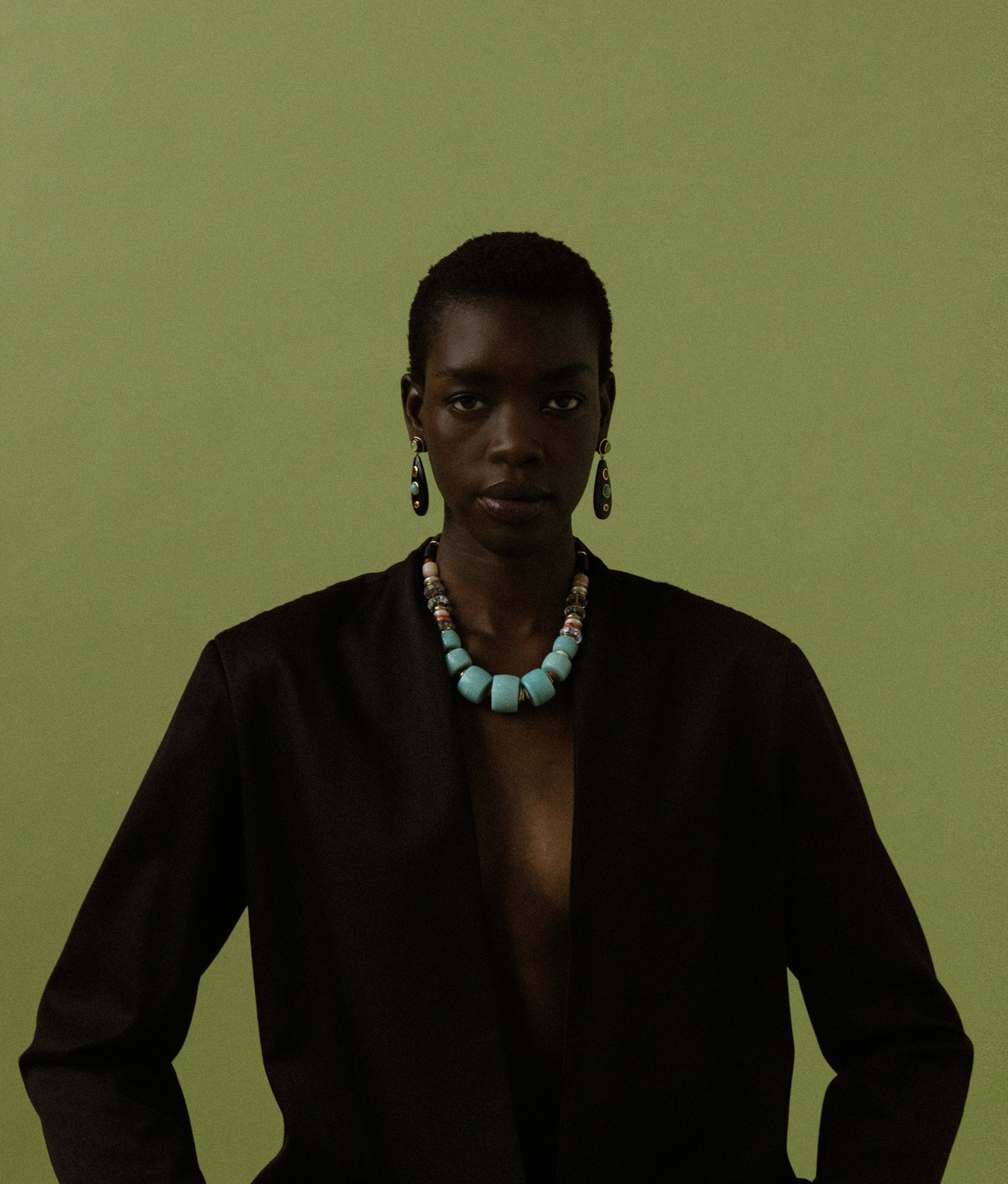 Model on green backdrop wears oversized black blazer with Regal Garden Necklace.