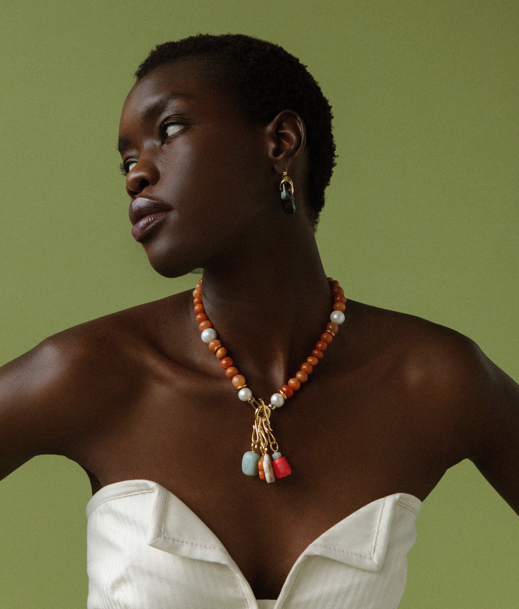 Model on green backdrop wears strapless white top and Mood Necklace in Red Aventurine with assorted mood charms.