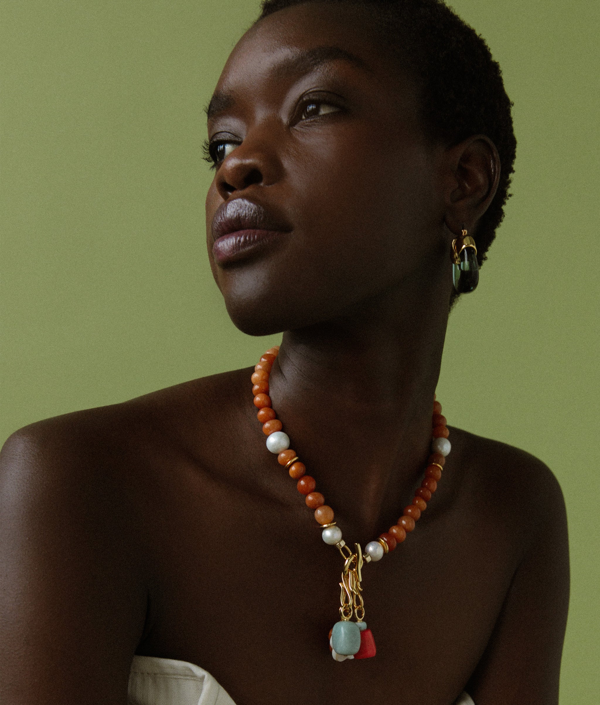 Model on green backdrop wears Mood Necklace in Red Aventurine with assorted mood charms.