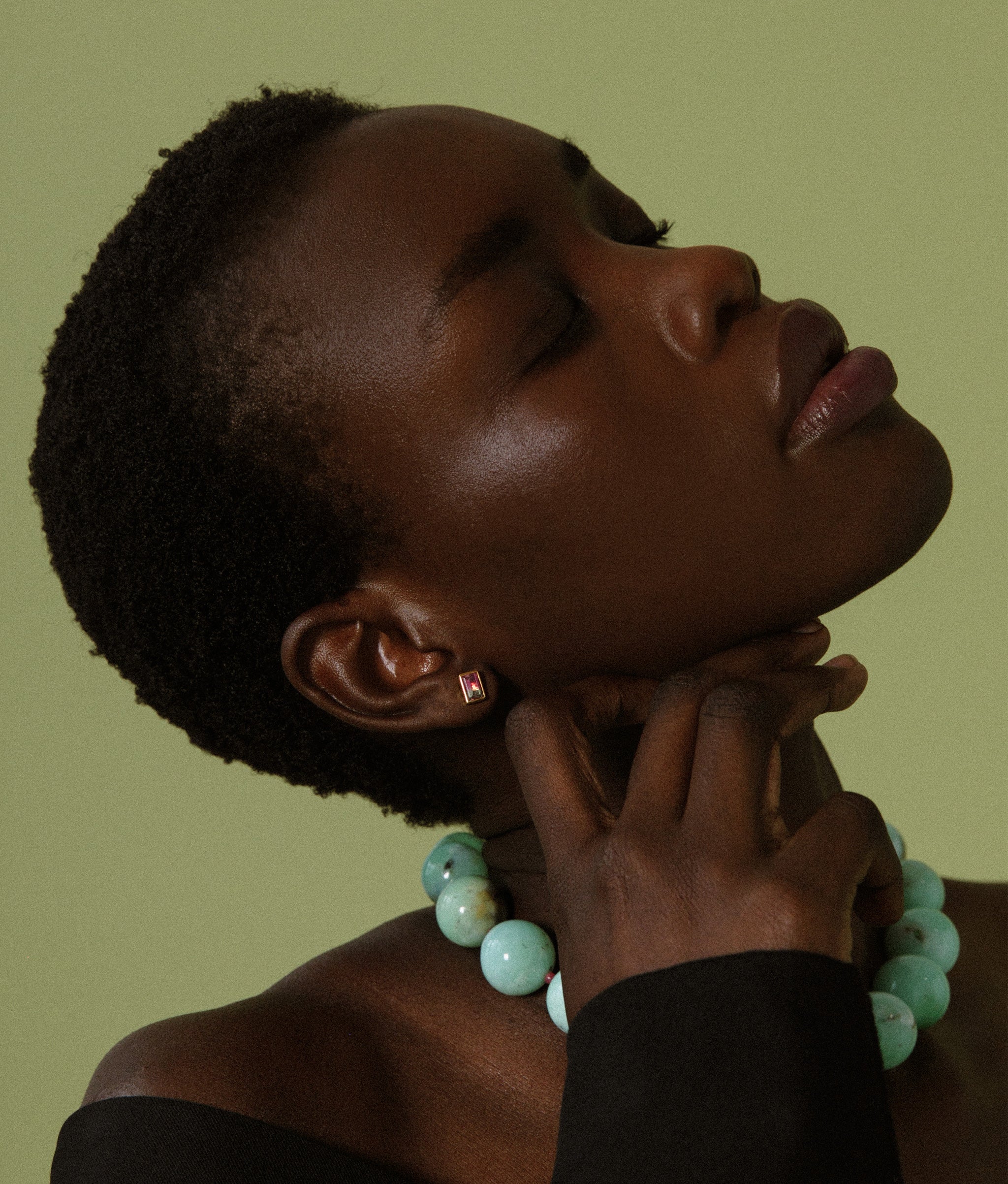 Model in profile on green backdrop wears Jumbo Chrysoprase, Ruby & 14k Gold Necklace.