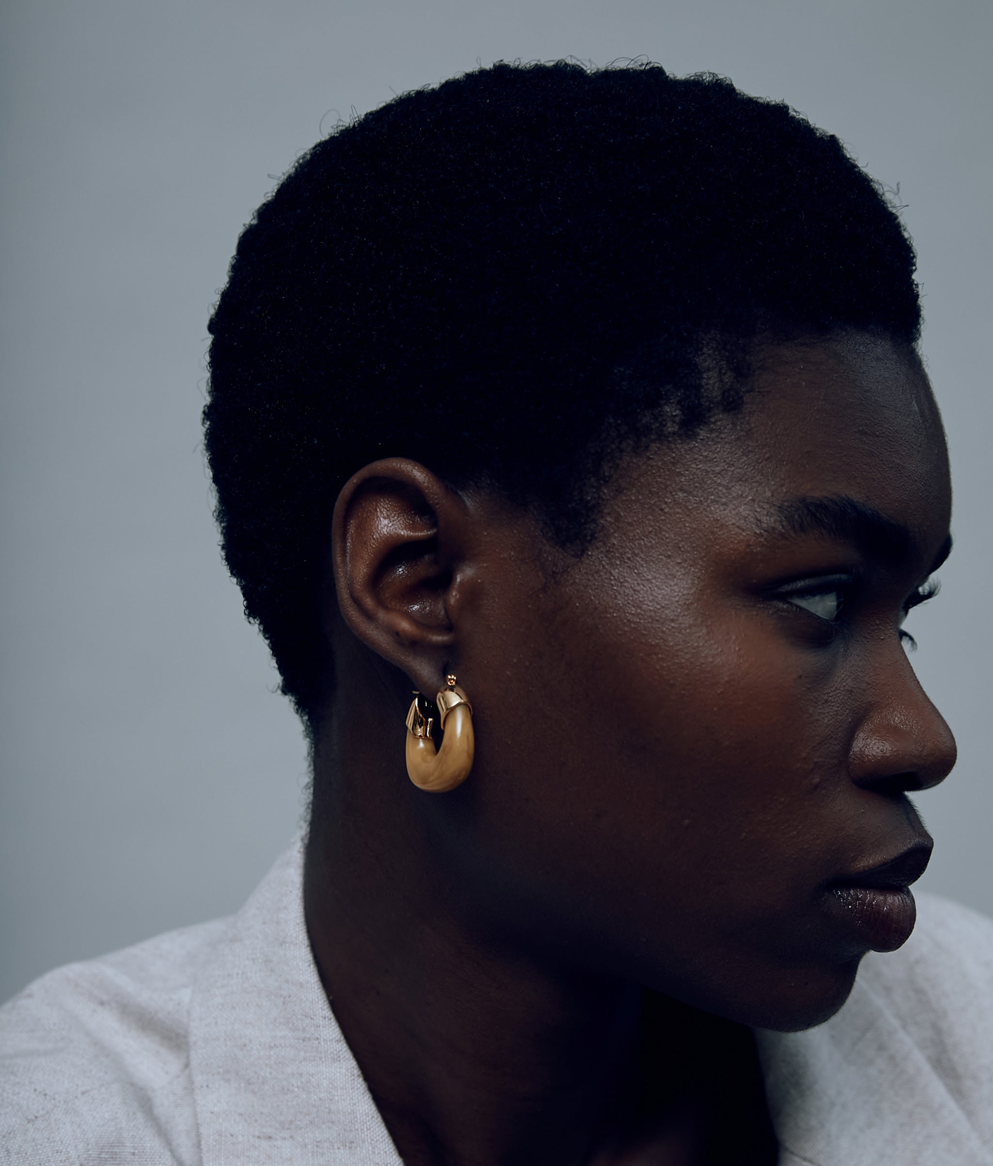 Model on grey background with the Mini Organic Hoops in Mocha.