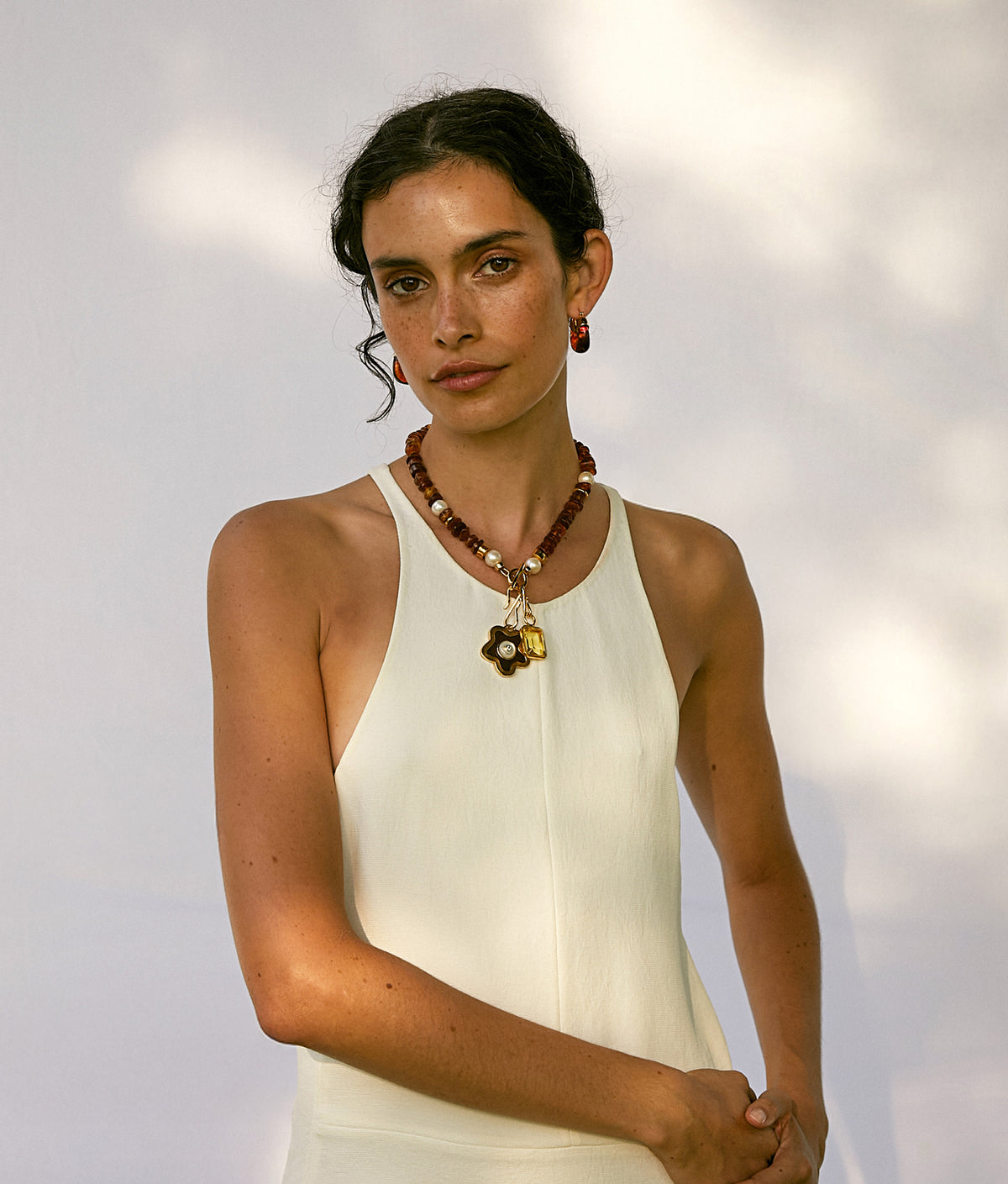 Model wears white tank top with Mood Necklace in Amber, Nana Pendant and Candyland Charm. With Mini Organic Hoops in Tortoise.