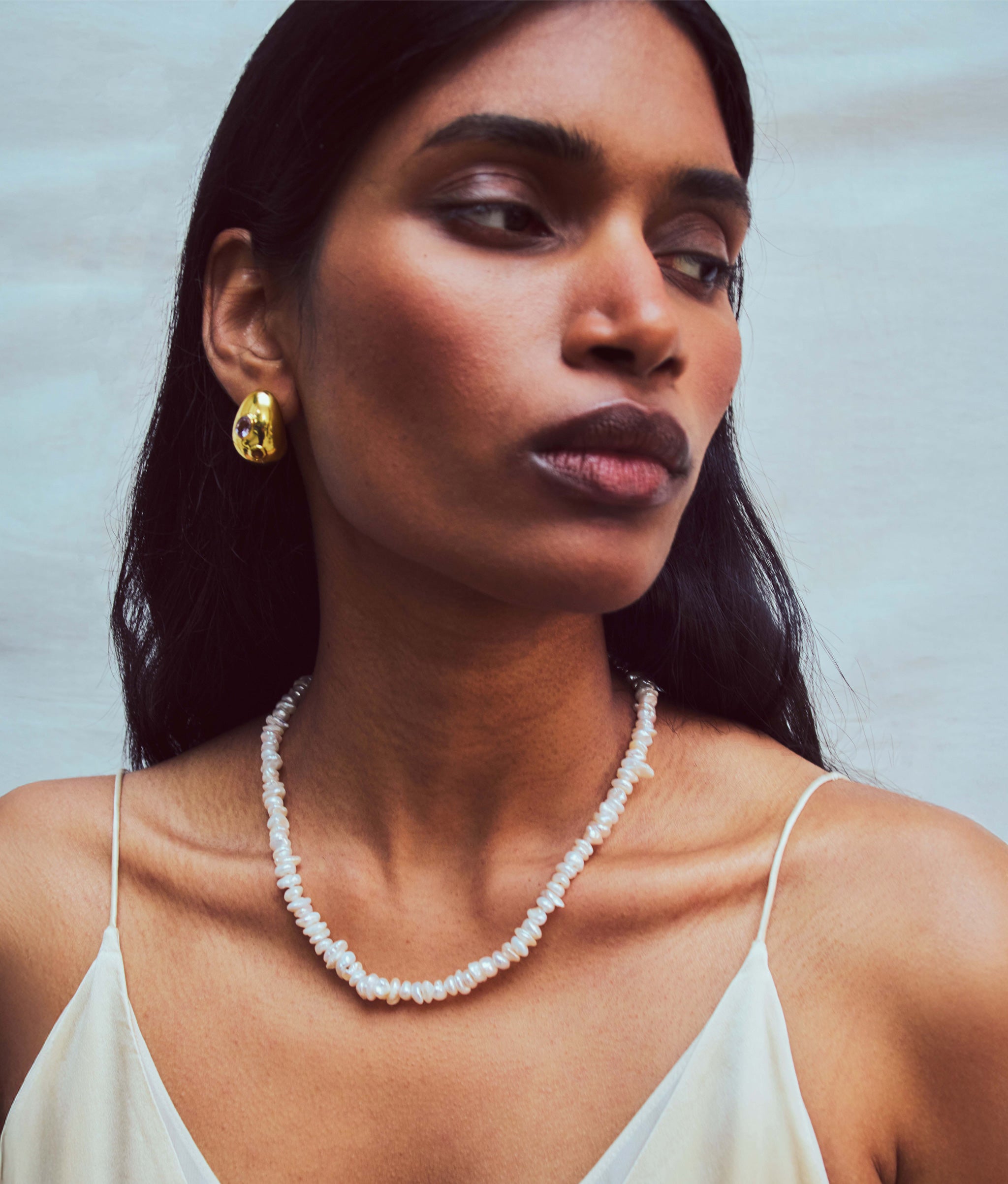 Model wears spaghetti-strap top with Mood Necklace in Pearl and Mini Arp Earrings in Studden Gold.
