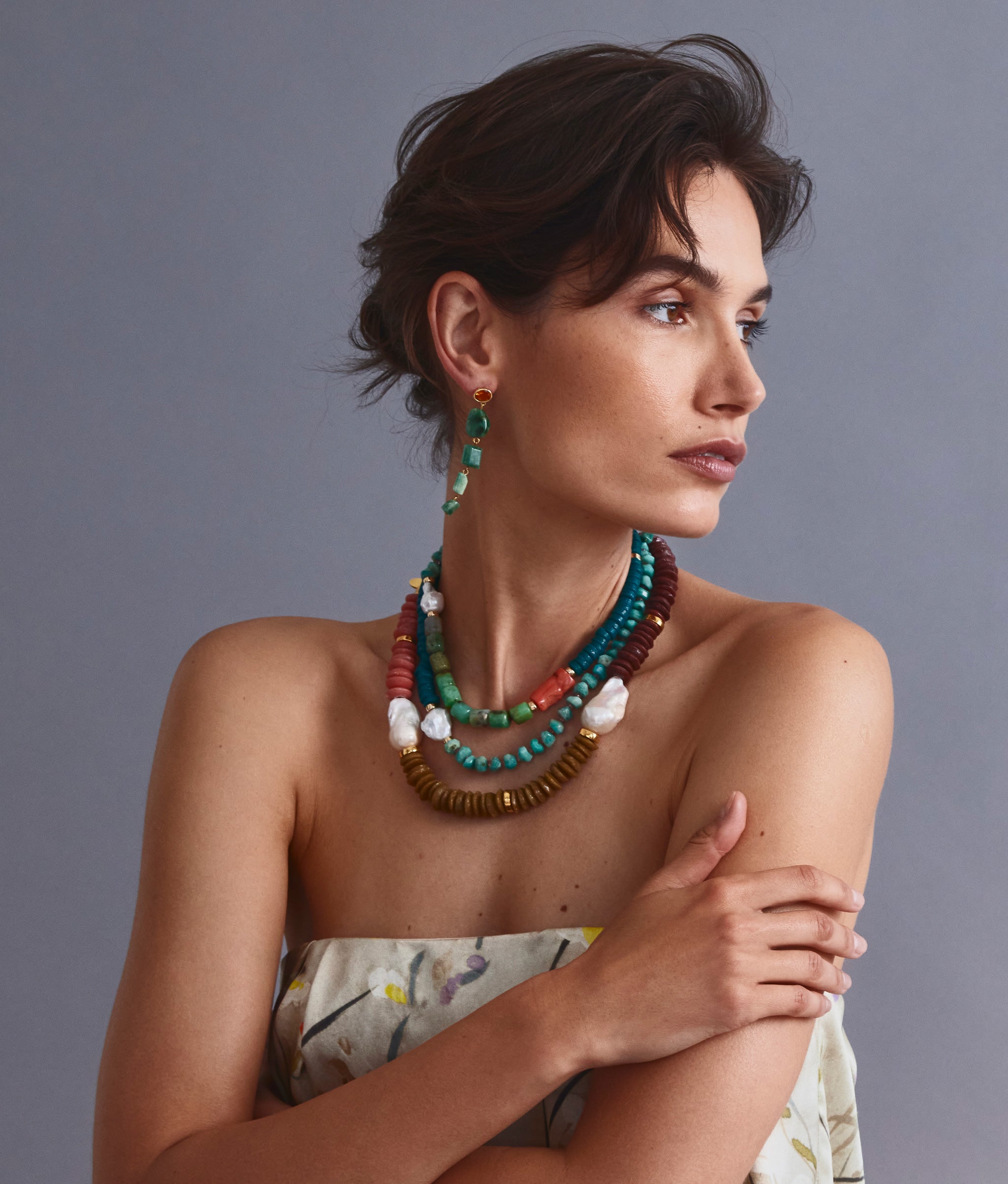 Model on grey backdrop wears strapless top with Cabana Necklace in Green Sea, Tavira Necklace in Lichen and Maya Earrings