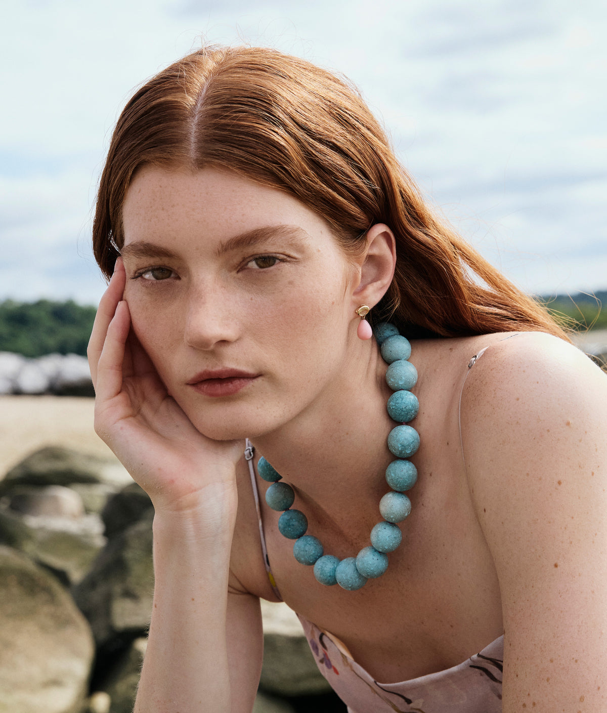 Model with hand on chin wears Drop Earrings in Lemon Quartz & Pink Opal and Turquoise & Ruby Necklace.