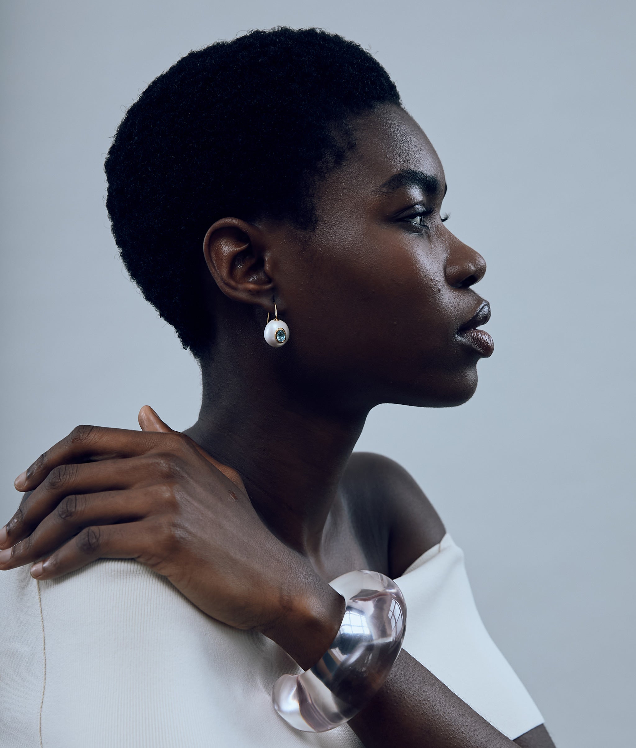 Model in profile wears white top with Arc Cuff in Lilac and Pearl Pablo Earrings