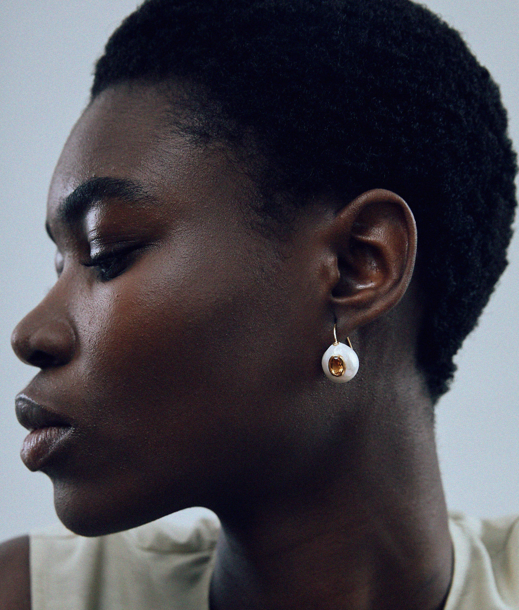 Close up of model on grey background wearing Pearl Pablo Earrings in Citrine.