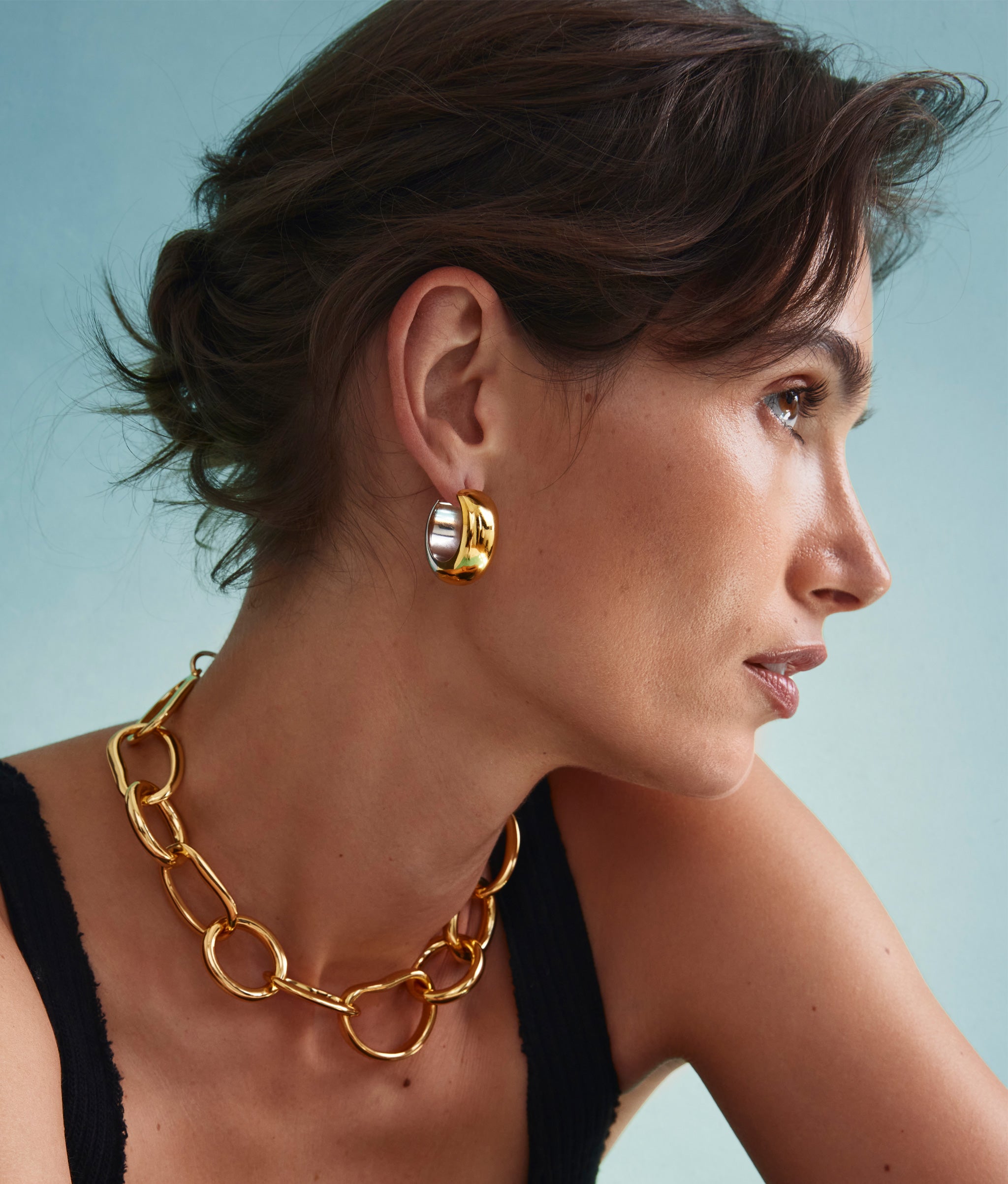 Model on blue backdrop wears black tank with Bubble Hoop Earrings and Porto Chain.