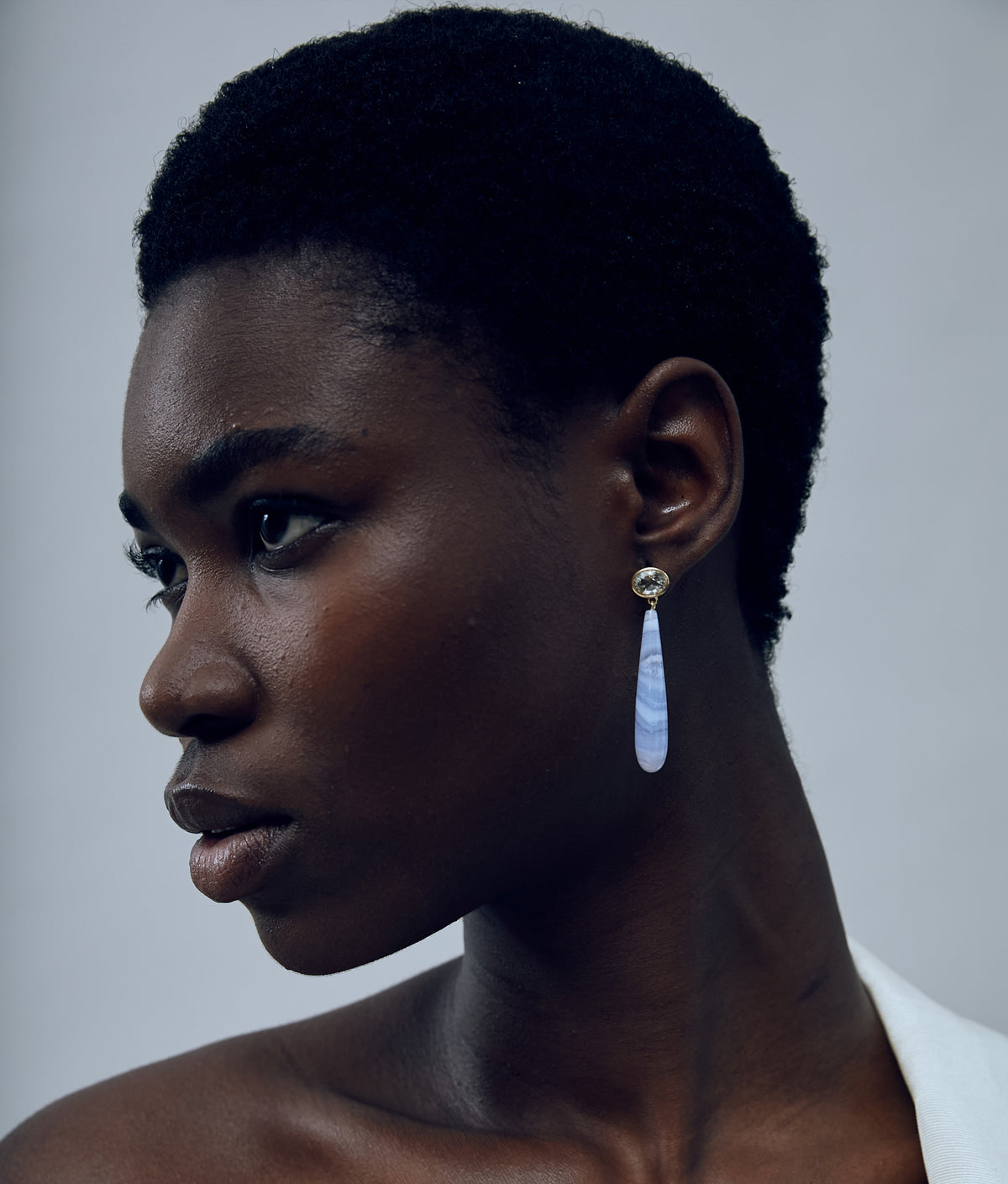 Another angle of model on grey background with 14k Gold Drop Earrings in Green Amethyst & Blue Lace Agate.