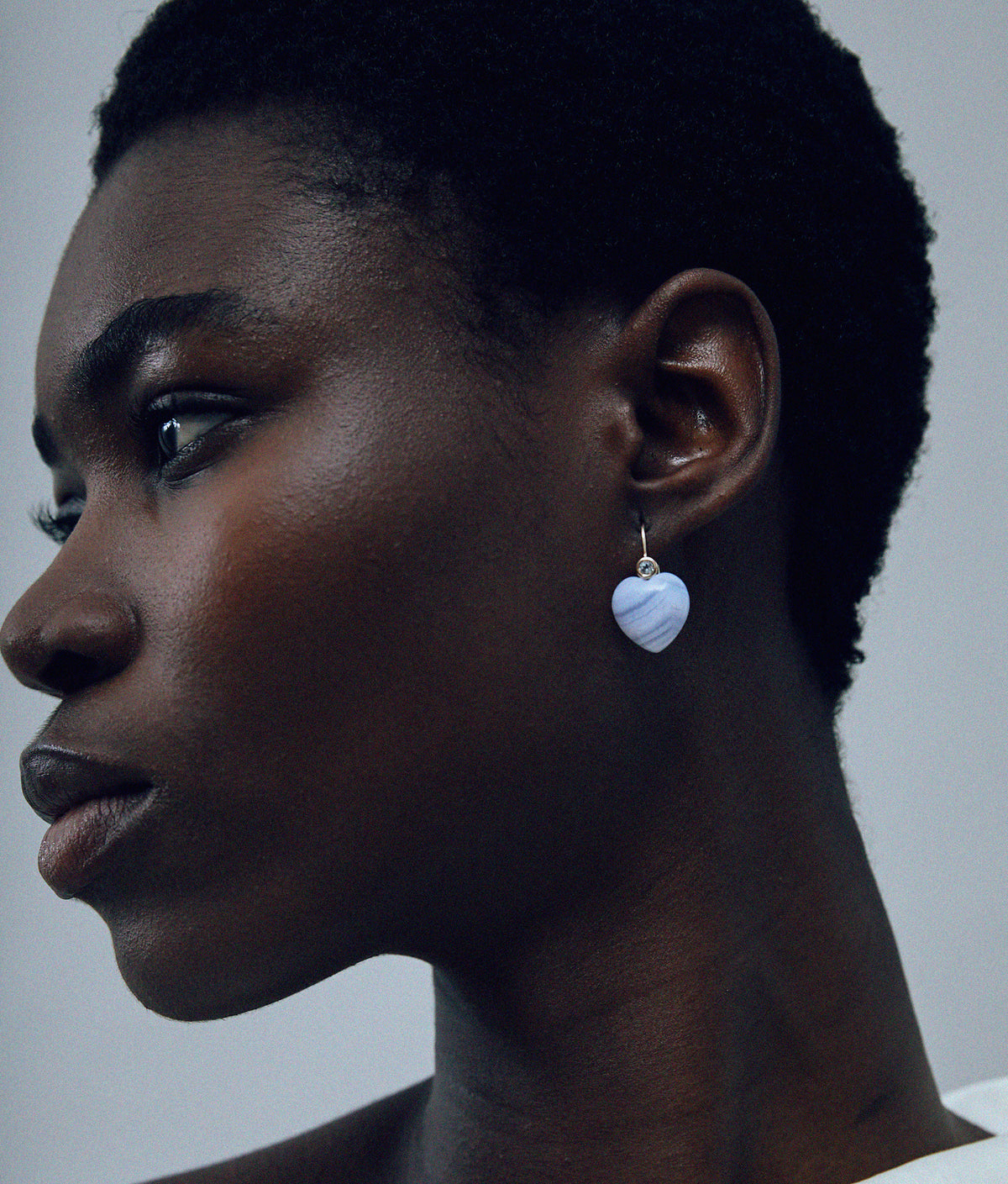 Model on grey background wearing the 14k Gold Amor Earrings in Sky Blue Topaz & Blue Lace Agate.
