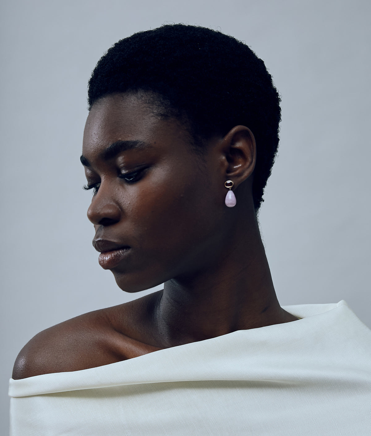 Model on grey background wearing the 14k Gold Drop Earrings in Garnet & Kunzite.