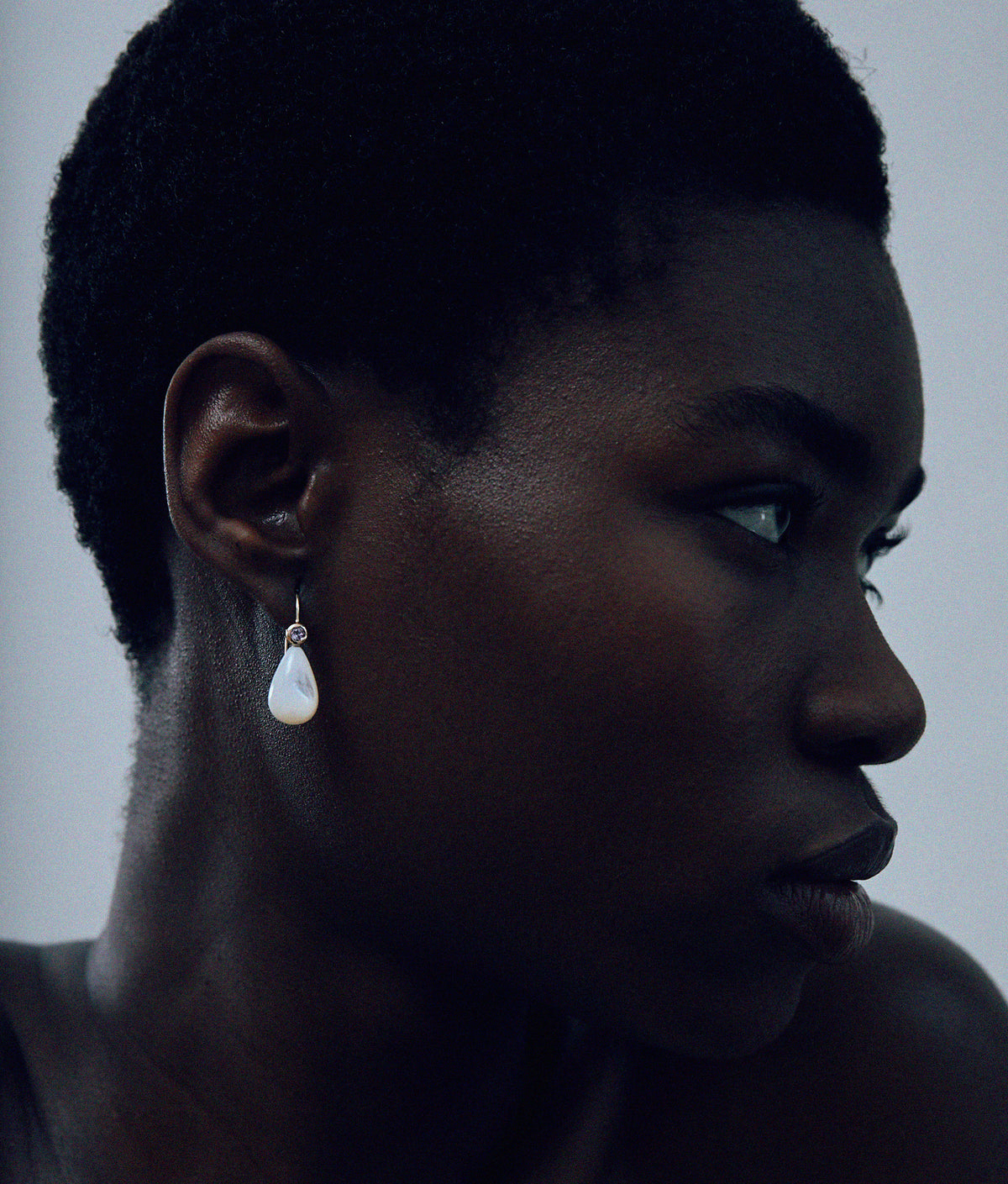 Model on grey background wearing the 14k Gold Drop Earrings in Pink Amethyst & Pearl.