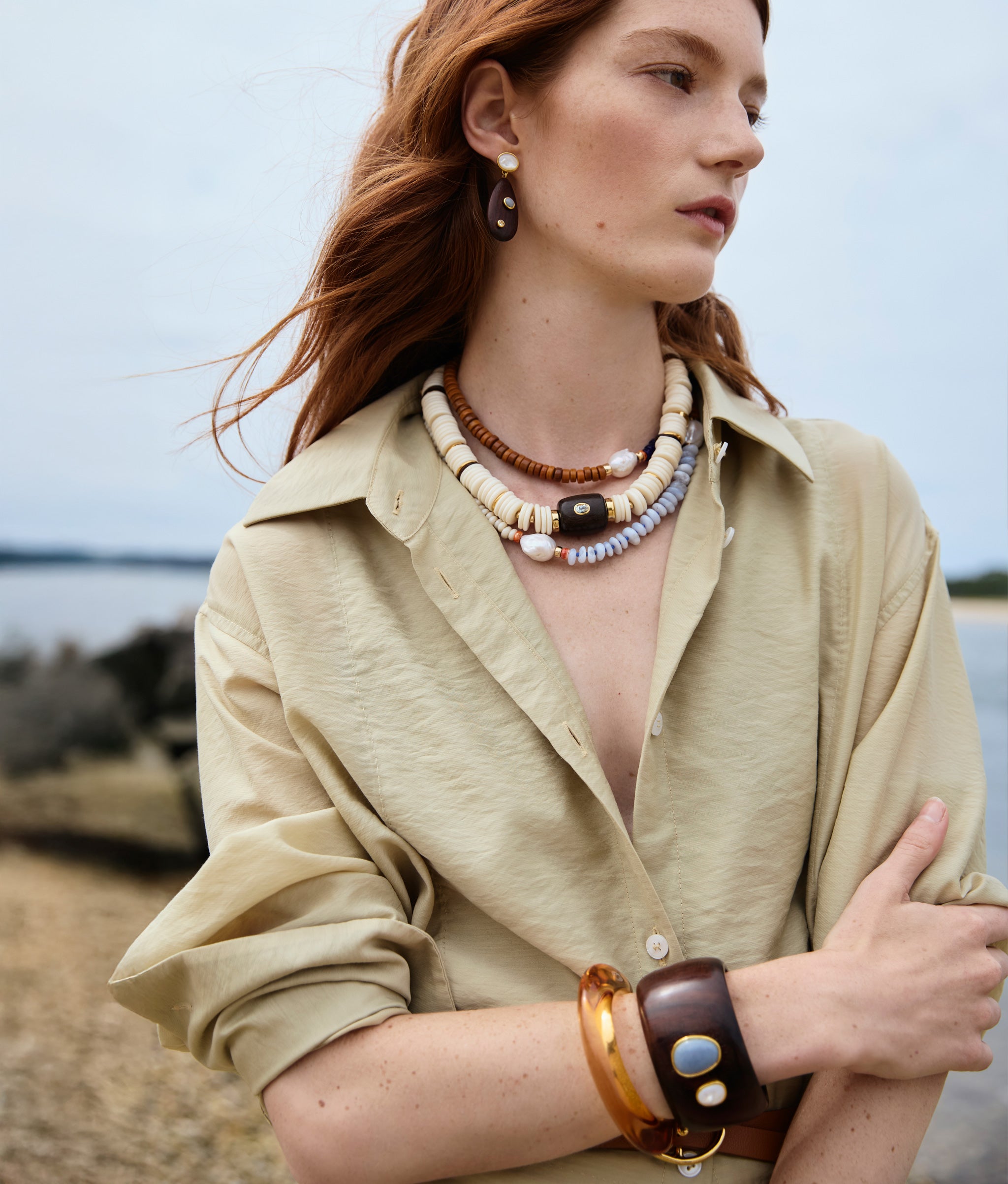 Model in New Moon Collar, Cabana Necklace in Coastline, Tamarind Drop Earrings, and stacked cuffs.