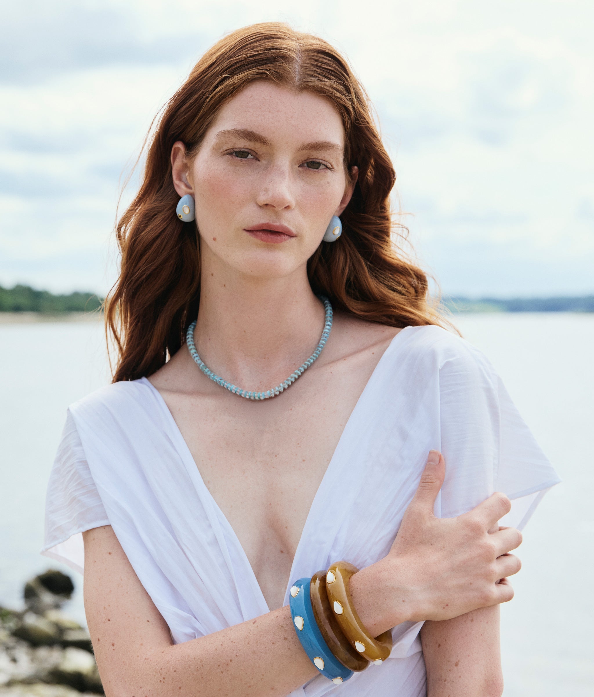 Model wears Mini Arp Earrings in Studded Mist, Santo Necklace in Mineral Blue, and stacked resin cuffs.