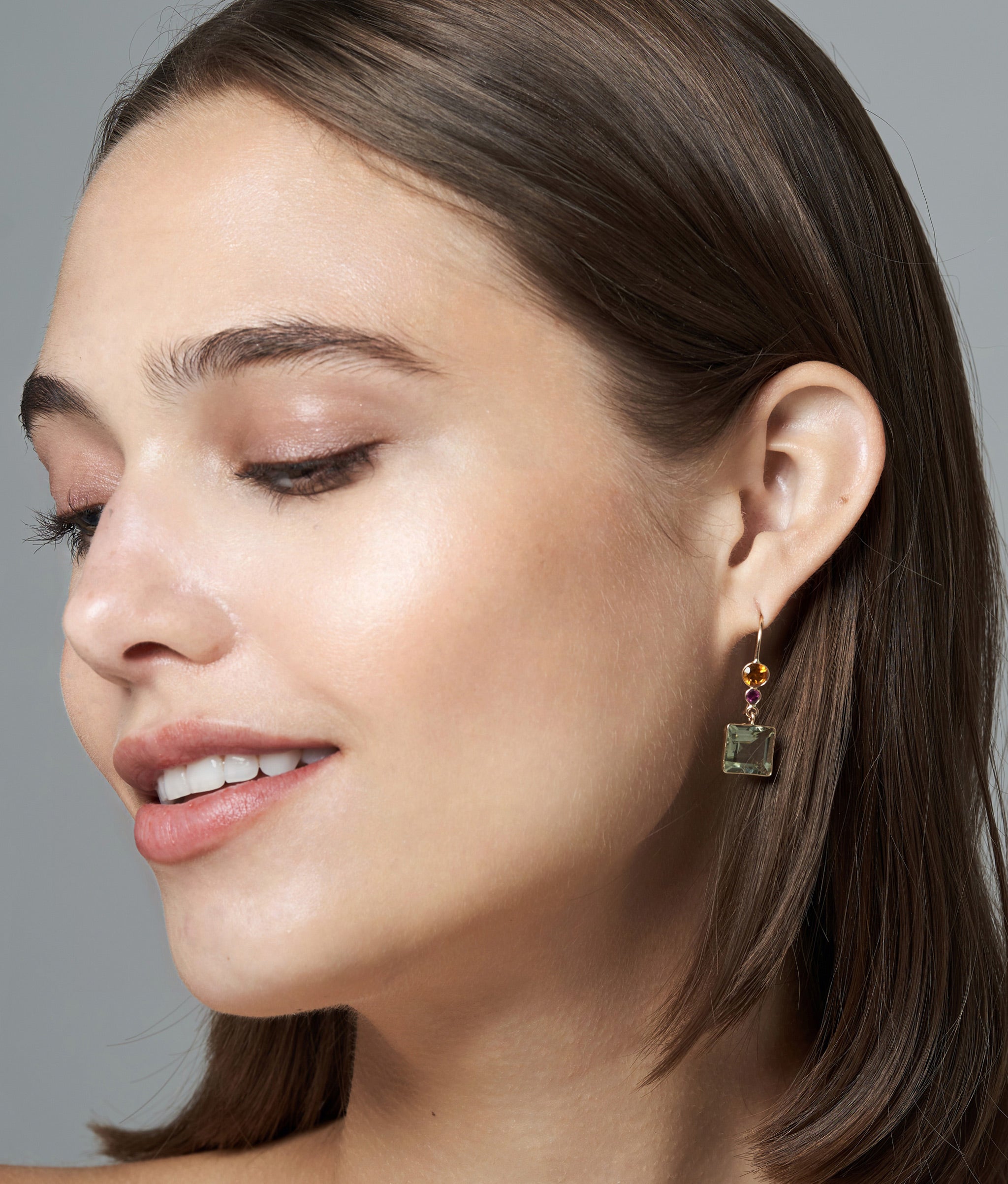 Model in profile on grey backdrop wears Lady Earrings in Green Amethyst.